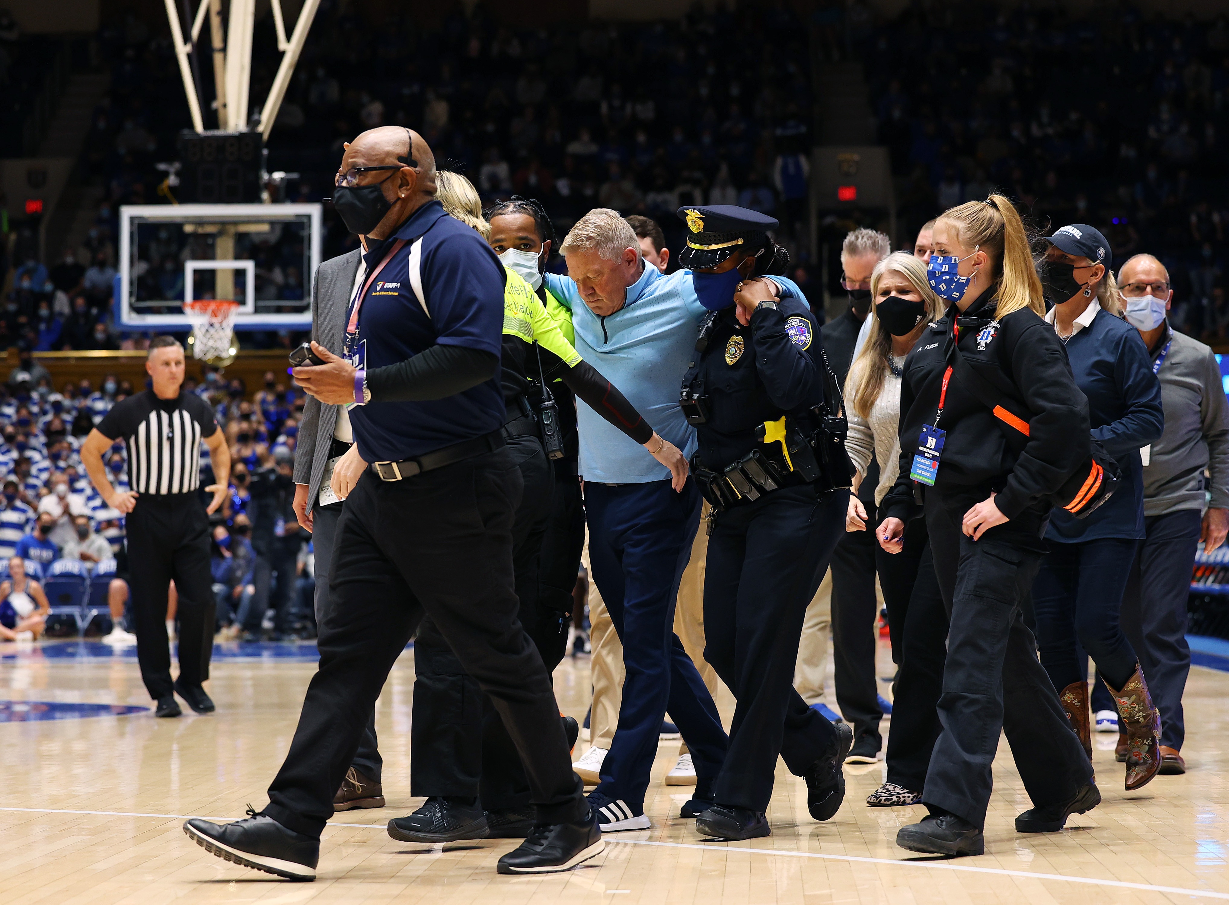 DURHAM, NORTH CAROLINA - NOVEMBER 22: Head coach Duggar Baucom of the Citadel Bulldogs is helped off of the floor after a medical incident during the first half of their game against the Duke Blue Devils at Cameron Indoor Stadium on November 22, 2021 in Durham, North Carolina. (Photo by Grant Halverson/Getty Images) DURHAM, NORTH CAROLINA - NOVEMBER 22: Head coach Duggar Baucom of the Citadel Bulldogs is helped off of the floor after a medical incident during the first half of their game against the Duke Blue Devils at Cameron Indoor Stadium on November 22, 2021 in Durham, North Carolina. (Photo by Grant Halverson/Getty Images)