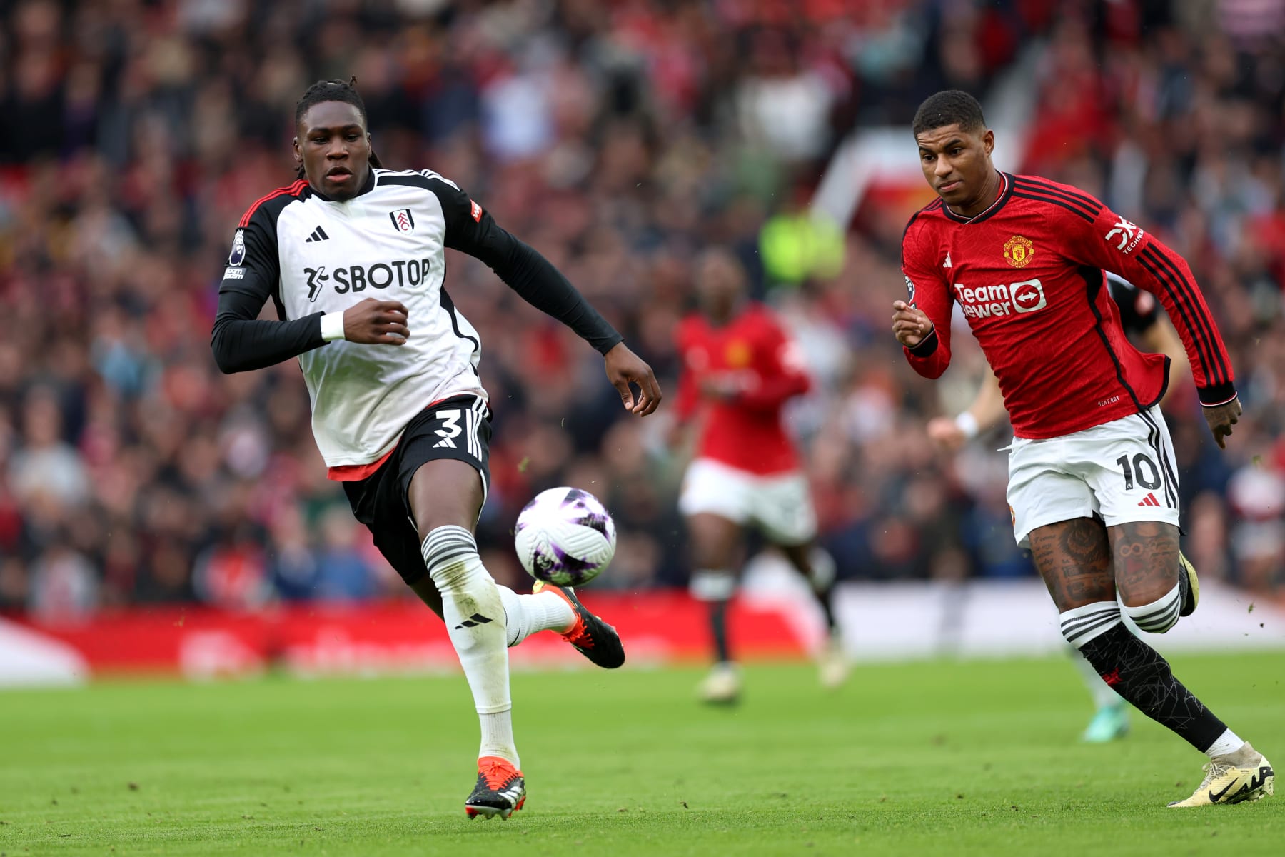 MANCHESTER, ENGLAND - FEBRUARY 24: Calvin Bassey and Marcus Rashford of Manchester United run for the ball during the Premier League match between Manchester United and Fulham FC at Old Trafford on February 24, 2024 in Manchester, England. (Photo by Clive Brunskill/Getty Images)