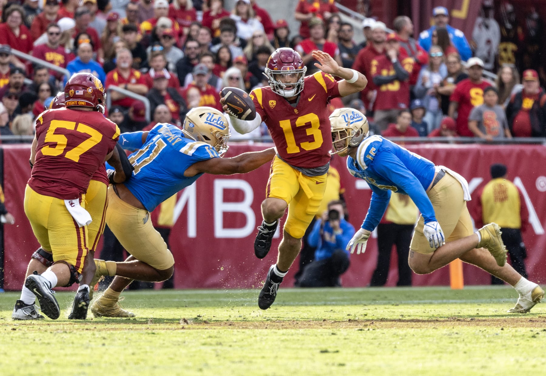 LOS ANGELES, CA - NOVEMBER 18, 2023: USC Trojans quarterback Caleb Williams leaps out of the pocket to avoid UCLA Bruins defensive lineman Gabriel Murphy (11) and UCLA Bruins defensive lineman Laiatu Latu (15) at the LA Memorial Coliseum on November 18, 2023 in Los Angeles, California.(Gina Ferazzi / Los Angeles Times via Getty Images)