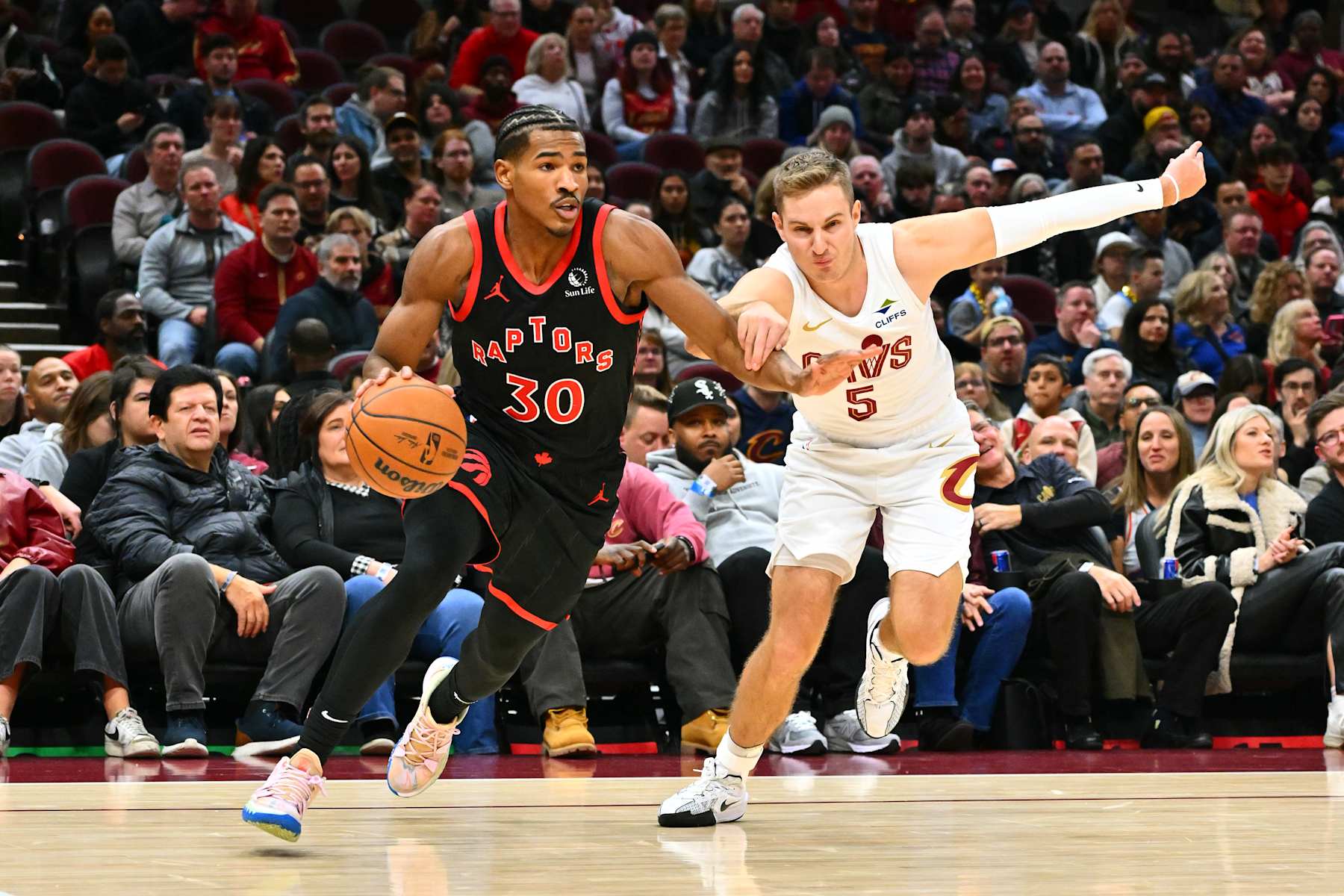 CLEVELAND, OHIO - NOVEMBER 24: Ochai Agbaji #30 of the Toronto Raptors drives to the basket around Sam Merrill #5 of the Cleveland Cavaliers during the third quarter at Rocket Mortgage Fieldhouse on November 24, 2024 in Cleveland, Ohio. The Cavaliers defeated the Raptors 122-108.NOTE TO USER: User expressly acknowledges and agrees that, by downloading and or using this photograph, User is consenting to the terms and conditions of the Getty Images License Agreement. (Photo by Jason Miller/Getty Images)