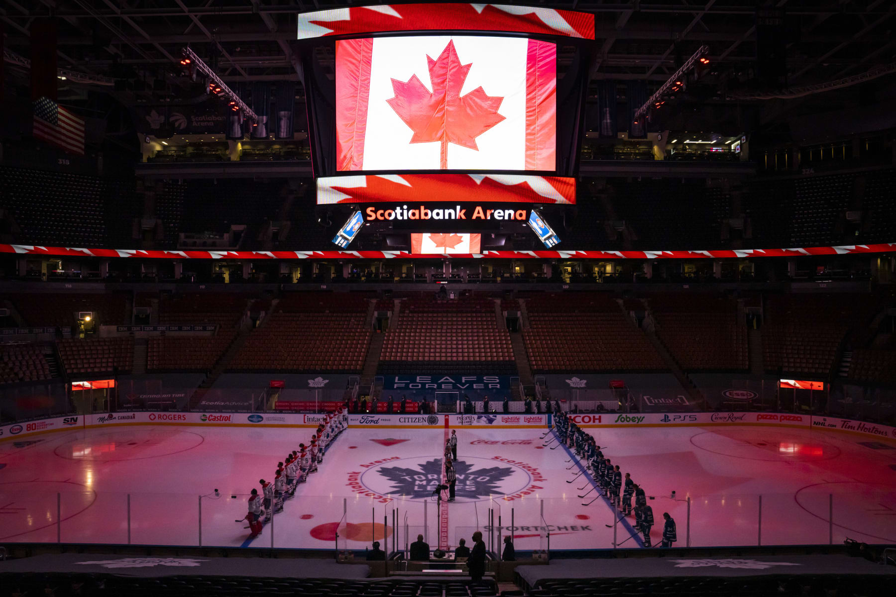 TORONTO, ON - JANUARY 13: Players stand for the national anthem as the screen displays a Canadian Flag at the Scotiabank Arena before the home opener between the Toronto Maple Leafs and Montreal Canadiens on January 13, 2021 in Toronto, Ontario, Canada. (Photo by Kevin Sousa/NHLI via Getty Images)