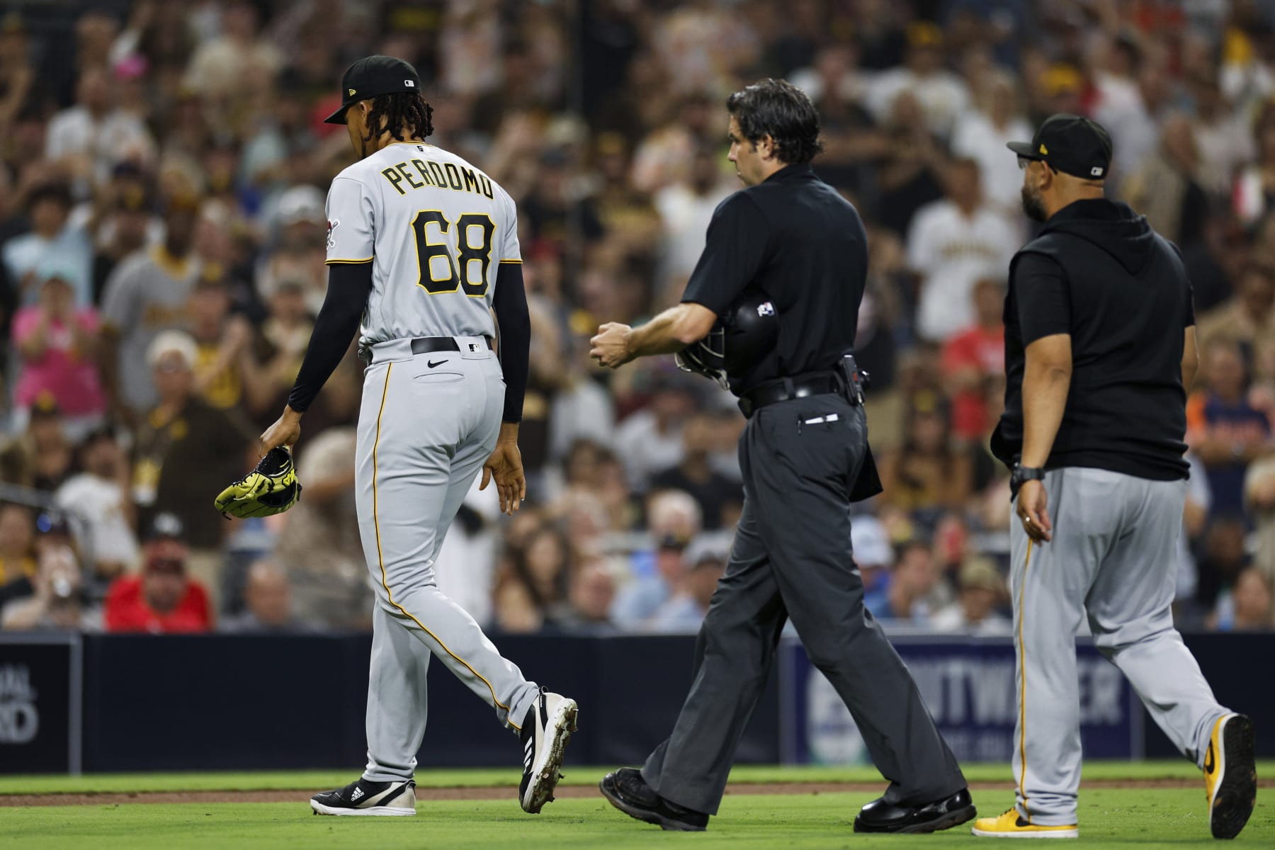 Pittsburgh Pirates relief pitcher Angel Perdomo (68) is escorted off the field by umpire John Tumpane, center, after hitting San Diego Padres' Manny Machado with a pitch during the seventh inning of a baseball game Tuesday, July 25, 2023, in San Diego. (AP Photo/Derrick Tuskan)