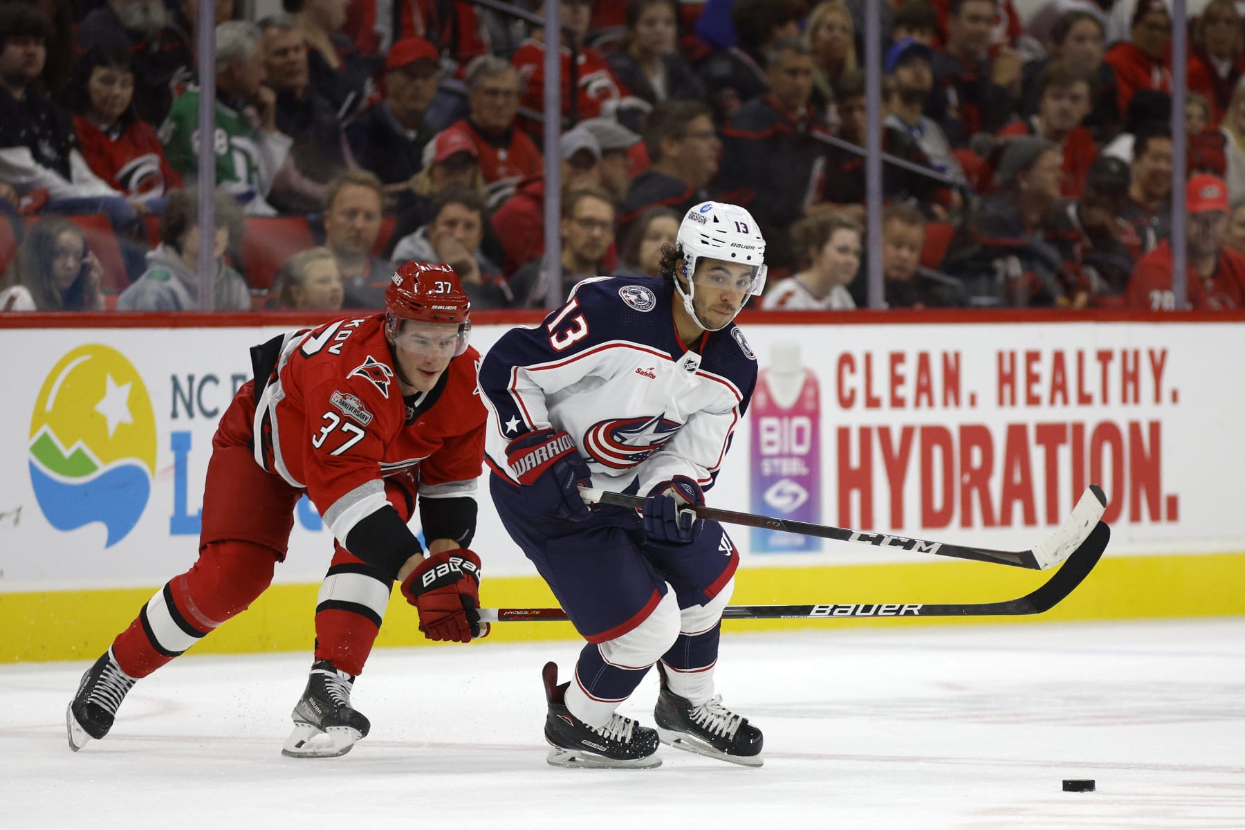 RALEIGH, NORTH CAROLINA - OCTOBER 12: Johnny Gaudreau #13 of the Columbus Blue Jackets skates with the puck while chased by Andrei Svechnikov #37 of the Carolina Hurricanes during the first period of the game at PNC Arena on October 12, 2022 in Raleigh, North Carolina. (Photo by Jared C. Tilton/Getty Images)