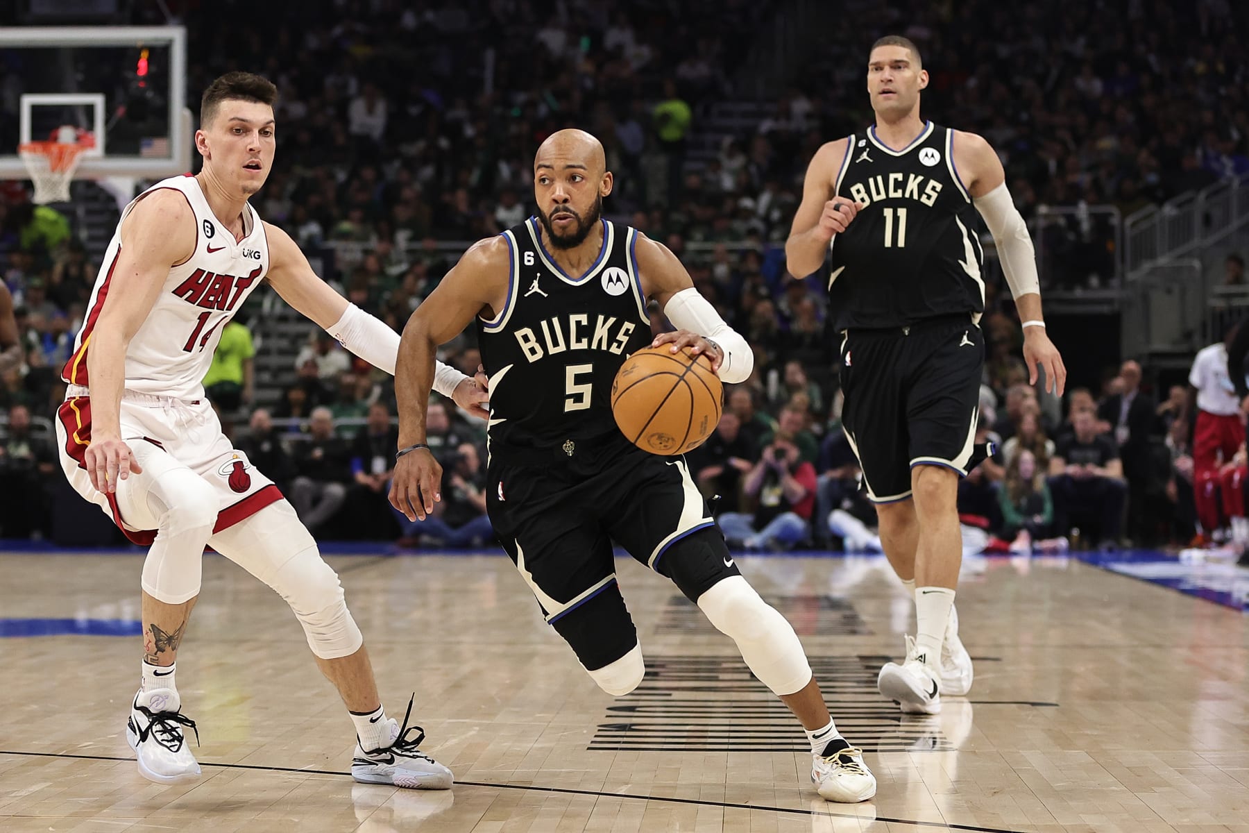 MILWAUKEE, WISCONSIN - APRIL 16: Jevon Carter #5 of the Milwaukee Bucks drives around Tyler Herro #14 of the Miami Heat during Game One of the Eastern Conference First Round Playoffs at Fiserv Forum on April 16, 2023 in Milwaukee, Wisconsin. Miami defeated Milwaukee 130-117. NOTE TO USER: User expressly acknowledges and agrees that, by downloading and or using this photograph, User is consenting to the terms and conditions of the Getty Images License Agreement. (Photo by Stacy Revere/Getty Images)