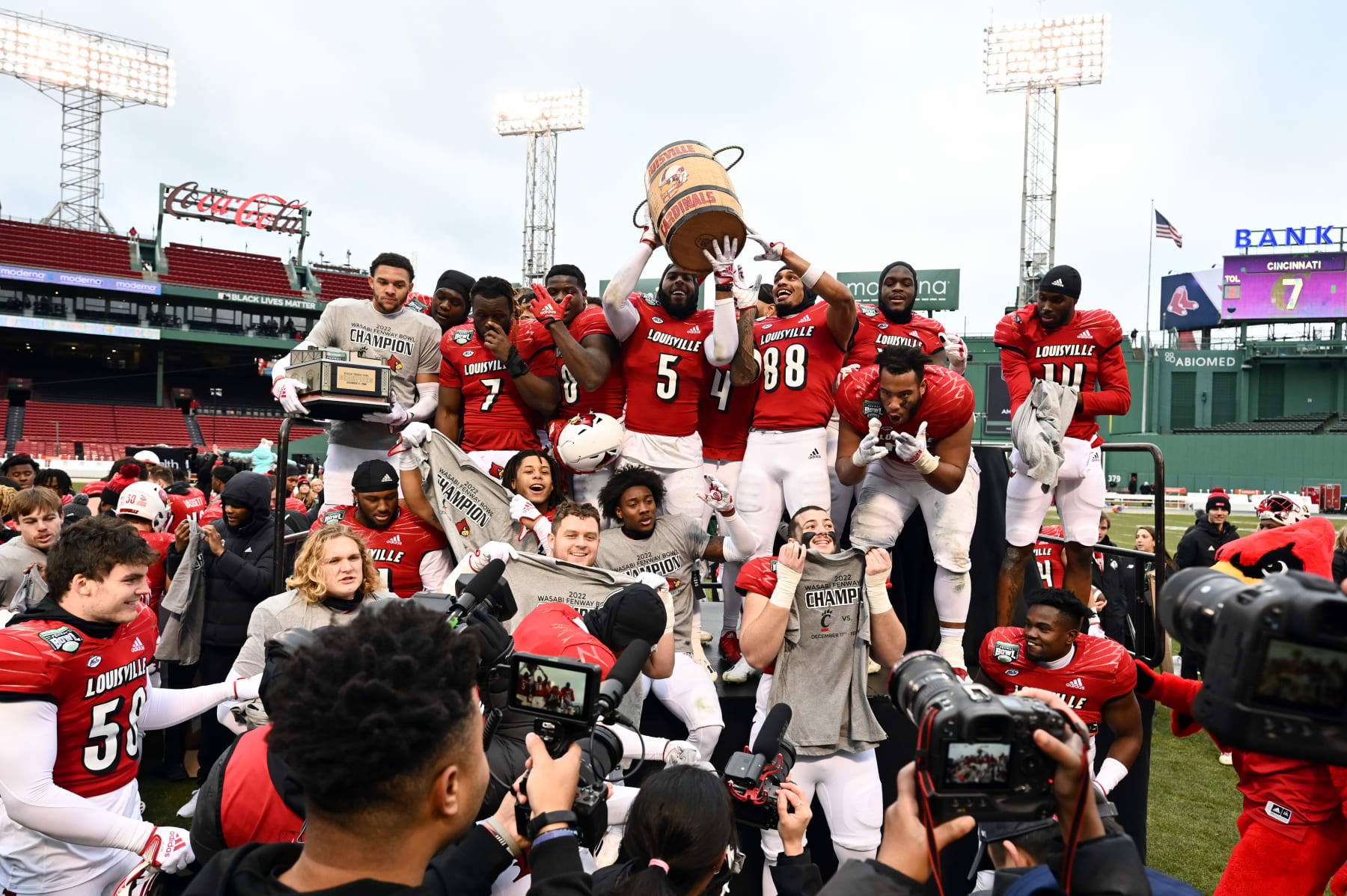 BOSTON, MASSACHUSETTS - DECEMBER 17: The Louisville Cardinals celebrate with the Wasabi Bowl and Keg of Nails trophies after beating the Cincinnati Bearcats at Fenway Park on December 17, 2022 in Boston, Massachusetts. (Photo by Brian Fluharty/Getty Images)