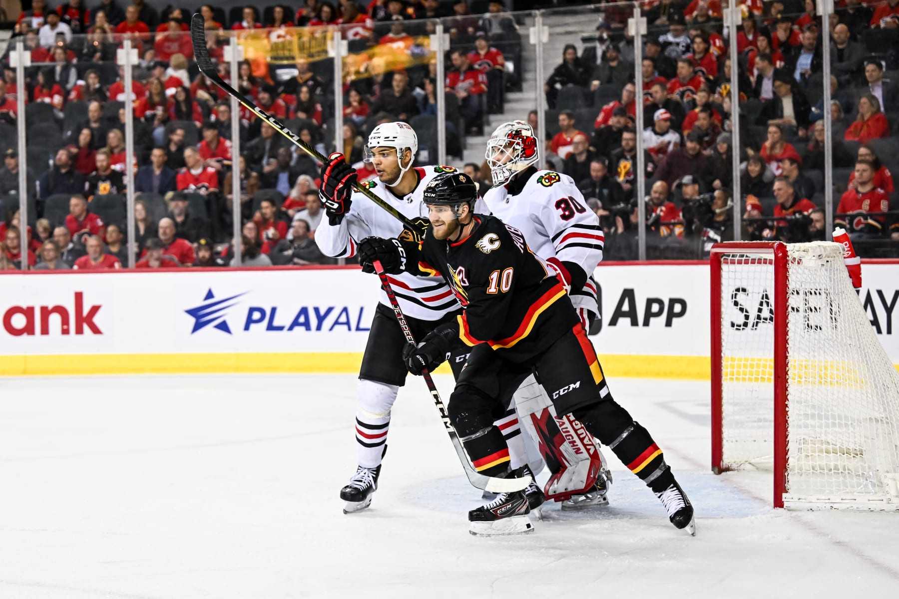 CALGARY, AB - JANUARY 26: Calgary Flames Right Wing Jonathan Huberdeau (10) and Chicago Blackhawks Defenceman Seth Jones (4) compete for position in front of Chicago Blackhawks Goalie Jaxson Stauber (30) during the third period of an NHL game between the Calgary Flames and the Chicago Blackhawks on January 26, 2023, at the Scotiabank Saddledome in Calgary, AB. (Photo by Brett Holmes/Icon Sportswire via Getty Images)