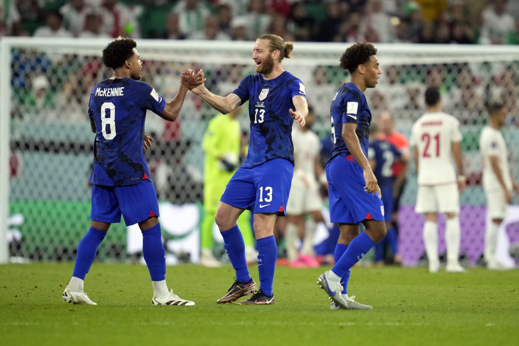 United States' Weston McKennie (8) and Tim Ream (13) celebrate after teammate Christian Pulisic scored a goal during the World Cup group B soccer match between Iran and the United States at the Al Thumama Stadium in Doha, Qatar, Tuesday, Nov. 29, 2022. (AP Photo/Ashley Landis)