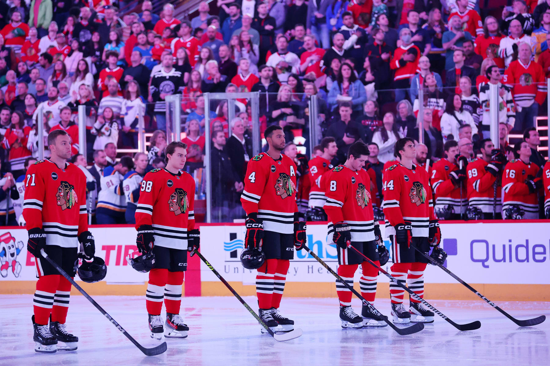 CHICAGO, ILLINOIS - SEPTEMBER 28: Taylor Hall #71, Connor Bedard #98, Seth Jones #4, Ryan Donato #8 and Wyatt Kaiser #44 of the Chicago Blackhawks observe the playing of the national anthem prior to the preseason game against the St. Louis Blues at the United Center on September 28, 2023 in Chicago, Illinois. (Photo by Michael Reaves/Getty Images)
