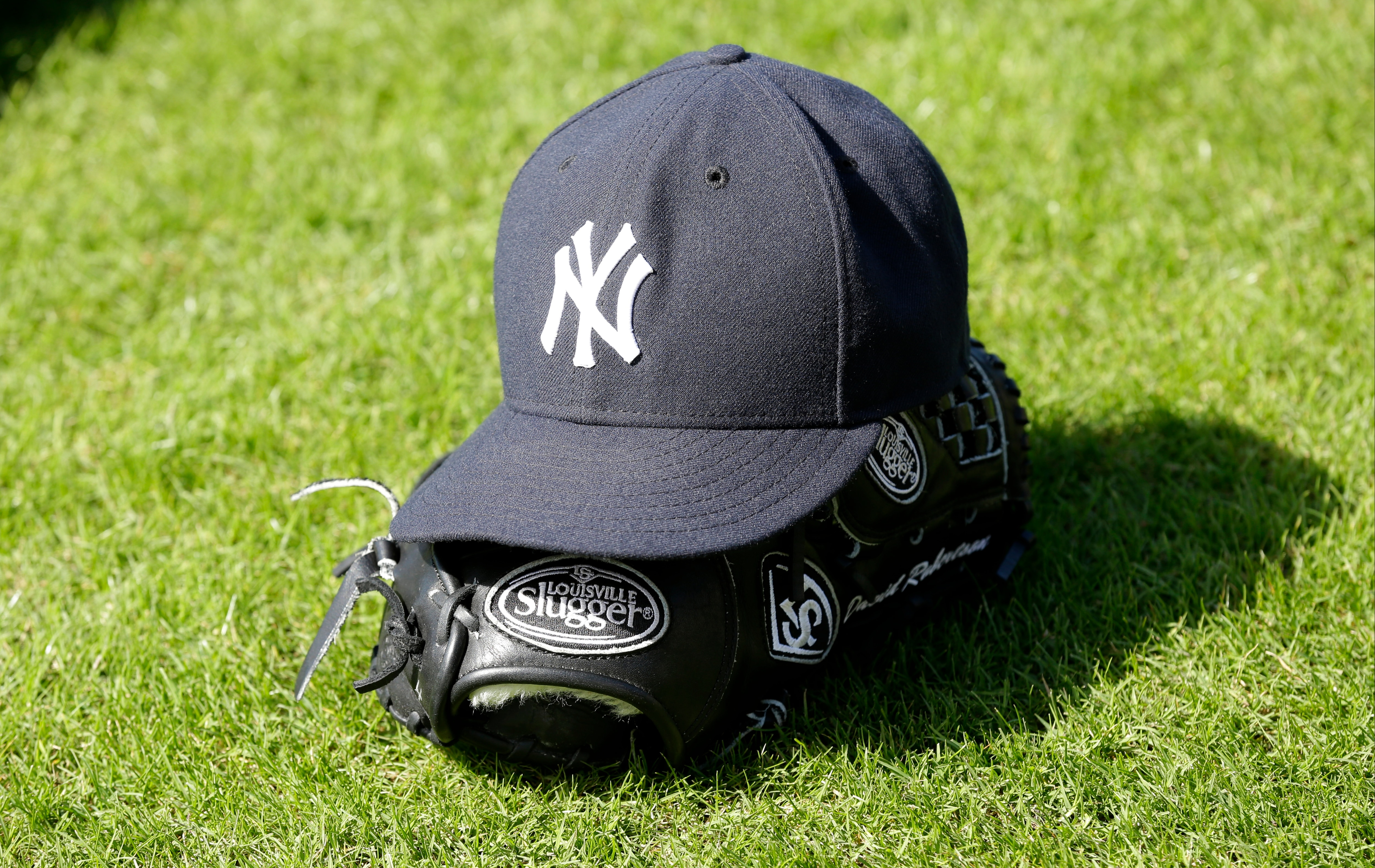 A New York Yankees hat and glove are seen on the field during spring training baseball practice Saturday, Feb. 15, 2014, in Tampa, Fla. (AP Photo/Charlie Neibergall)
