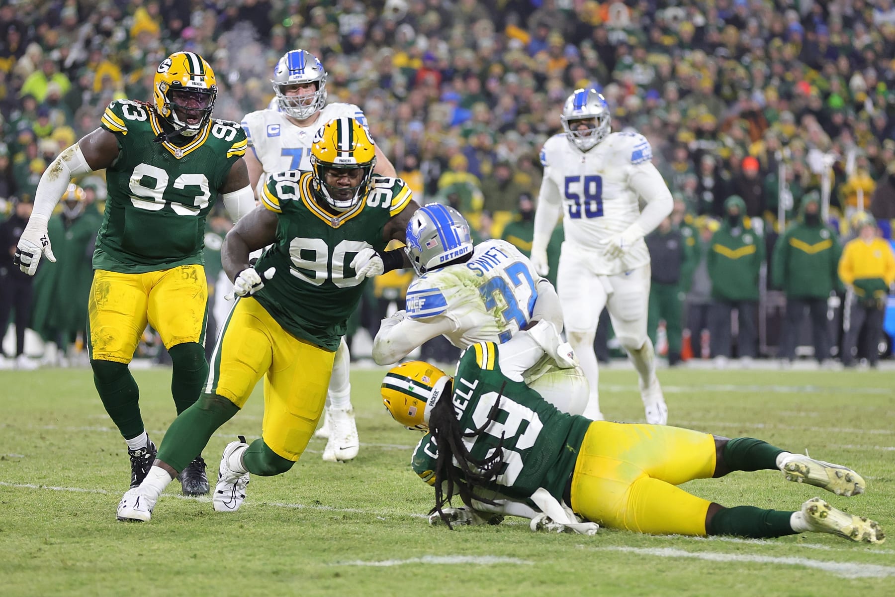 GREEN BAY, WISCONSIN - JANUARY 08: D'Andre Swift #32 of the Detroit Lions is brought down by De'Vondre Campbell #59 and Jarran Reed #90 of the Green Bay Packers during a game at Lambeau Field on January 08, 2023 in Green Bay, Wisconsin. The Lions defeated the Packers 20-16. (Photo by Stacy Revere/Getty Images)