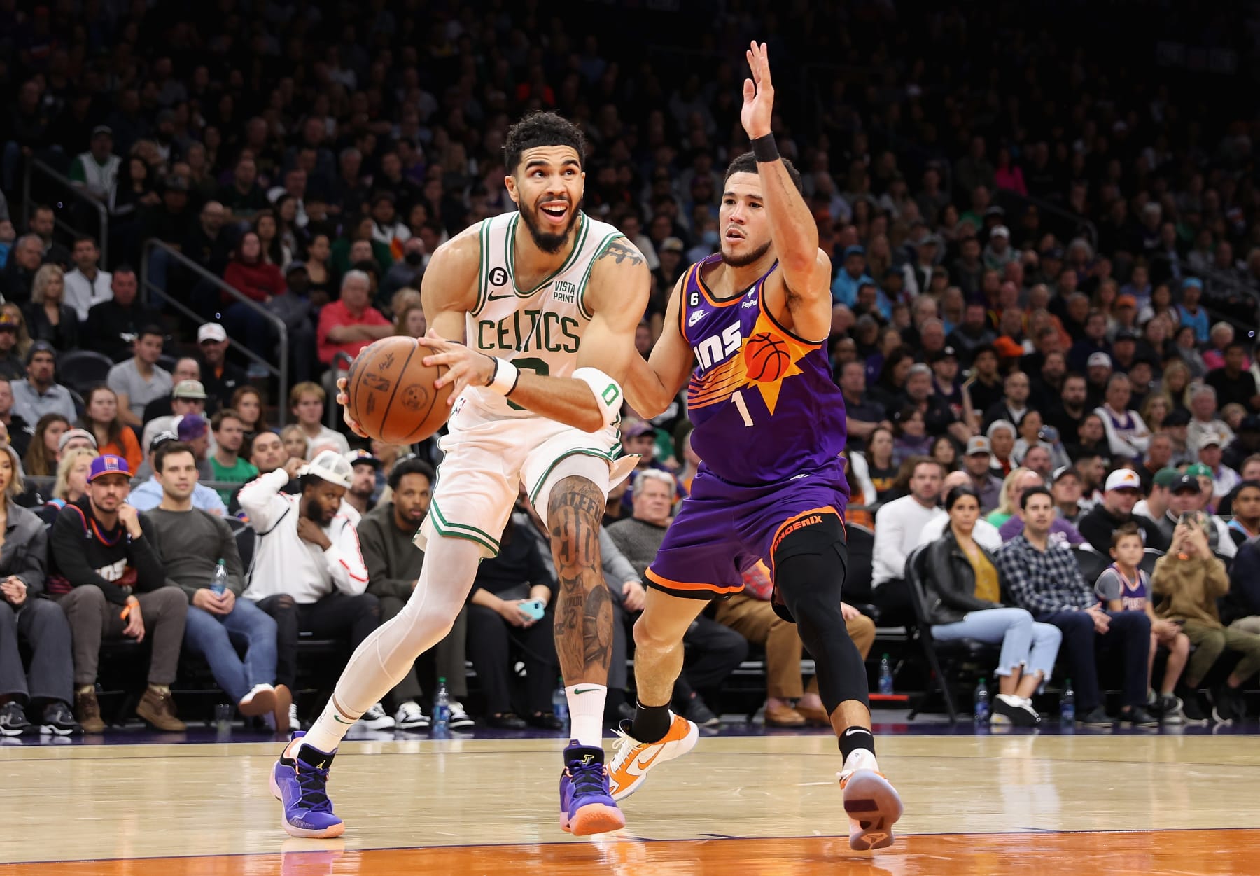 PHOENIX, ARIZONA - DECEMBER 07: Jayson Tatum #0 of the Boston Celtics drives the ball past Devin Booker #1 of the Phoenix Suns during the first half of the NBA game at Footprint Center on December 07, 2022 in Phoenix, Arizona. NOTE TO USER: User expressly acknowledges and agrees that, by downloading and or using this photograph, User is consenting to the terms and conditions of the Getty Images License Agreement. (Photo by Christian Petersen/Getty Images)