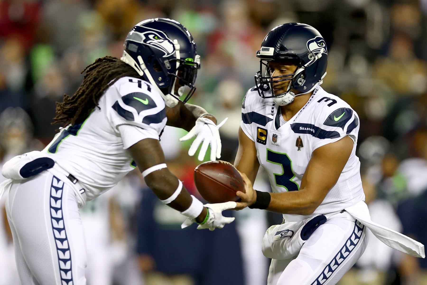 LANDOVER, MARYLAND - NOVEMBER 29: Russell Wilson #3 of the Seattle Seahawks hands the ball off to teammate Alex Collins #41 in the first quarter against the Washington Football Team at FedExField on November 29, 2021 in Landover, Maryland. (Photo by Todd Olszewski/Getty Images)