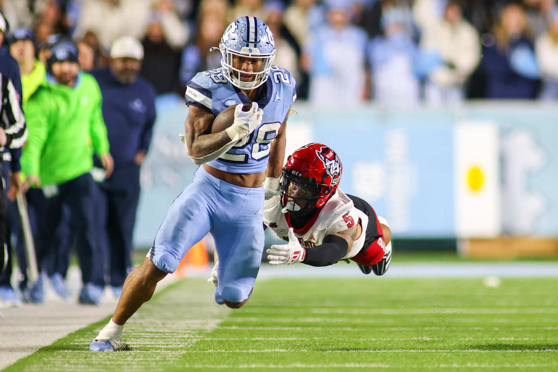 CHAPEL HILL, NC - NOVEMBER 30: North Carolina State Wolfpack safety DK Kaufman (5) attempts to tackle North Carolina Tar Heels running back Omarion Hampton (28) during the college basketball game between the North Carolina Tar Heels and the North Carolina State Wolfpack on November 30, 2024 at Kenan Memorial Stadium in Chapel Hill, NC. (Photo by Nicholas Faulkner/Icon Sportswire via Getty Images)