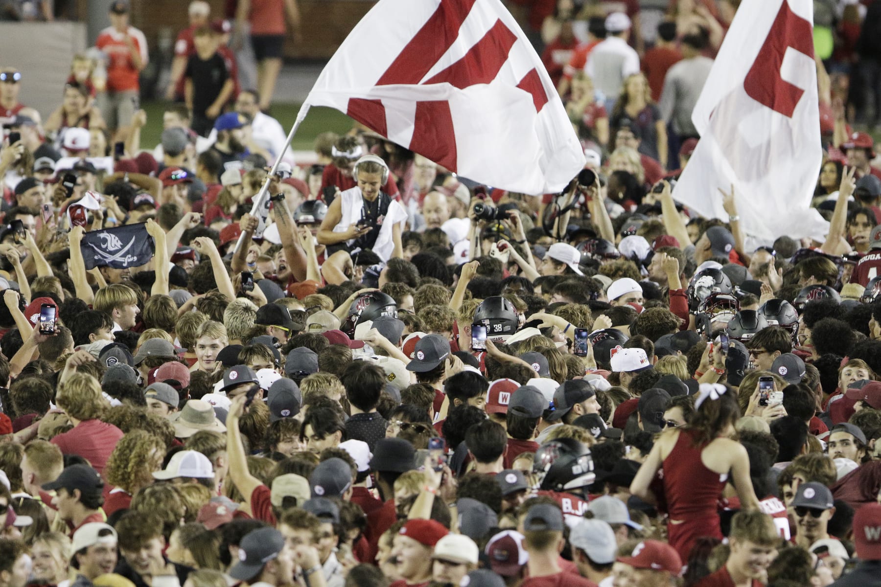 Washington State fans and players celebrate on the field after team's win over Wisconsin in an NCAA college football game, Saturday, Sept. 9, 2023, in Pullman, Wash. (AP Photo/Young Kwak)
