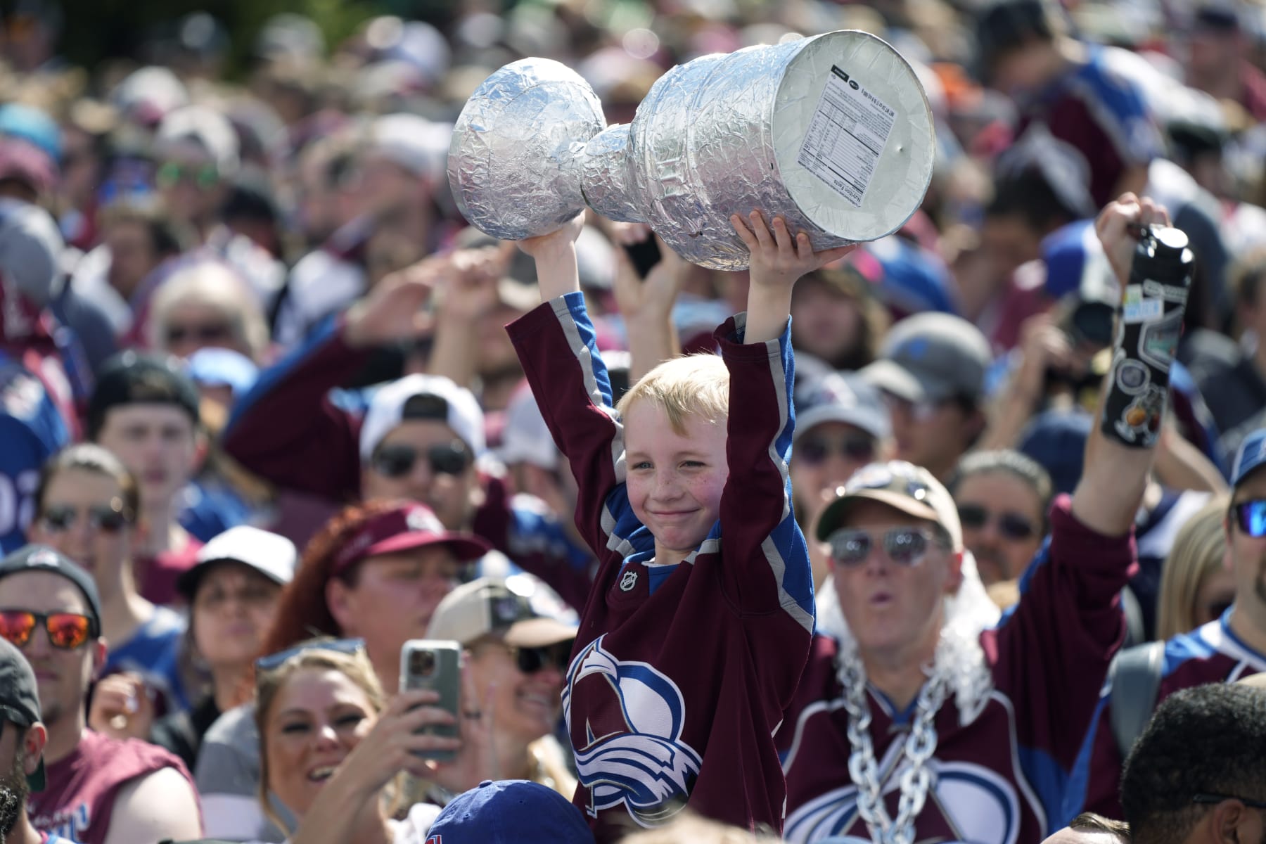 A Colorado Avalanche fan holds up a replica of the Stanley Cup during a rally outside the City/County Building for the NHL hockey champions after a parade through the streets of downtown Thursday, June 30, 2022, in Denver. (AP Photo/David Zalubowski)
