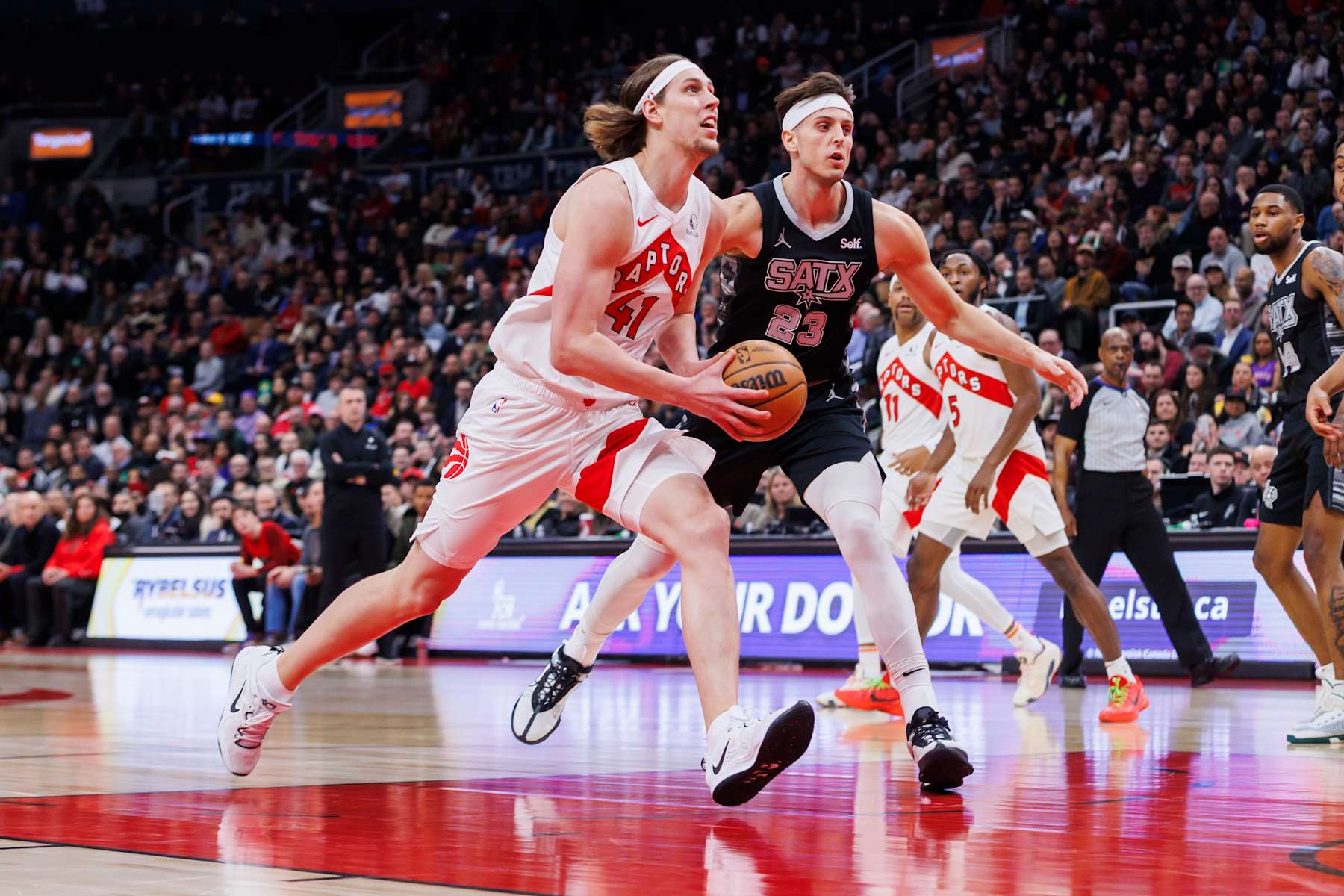 TORONTO, CANADA - FEBRUARY 12: Kelly Olynyk #41 of the Toronto Raptors drives to the net against Zach Collins #23 of the San Antonio Spurs in the first half of their NBA game at Scotiabank Arena on February 12, 2024 in Toronto, Canada. NOTE TO USER: User expressly acknowledges and agrees that, by downloading and or using this photograph, User is consenting to the terms and conditions of the Getty Images License Agreement. (Photo by Cole Burston/Getty Images)