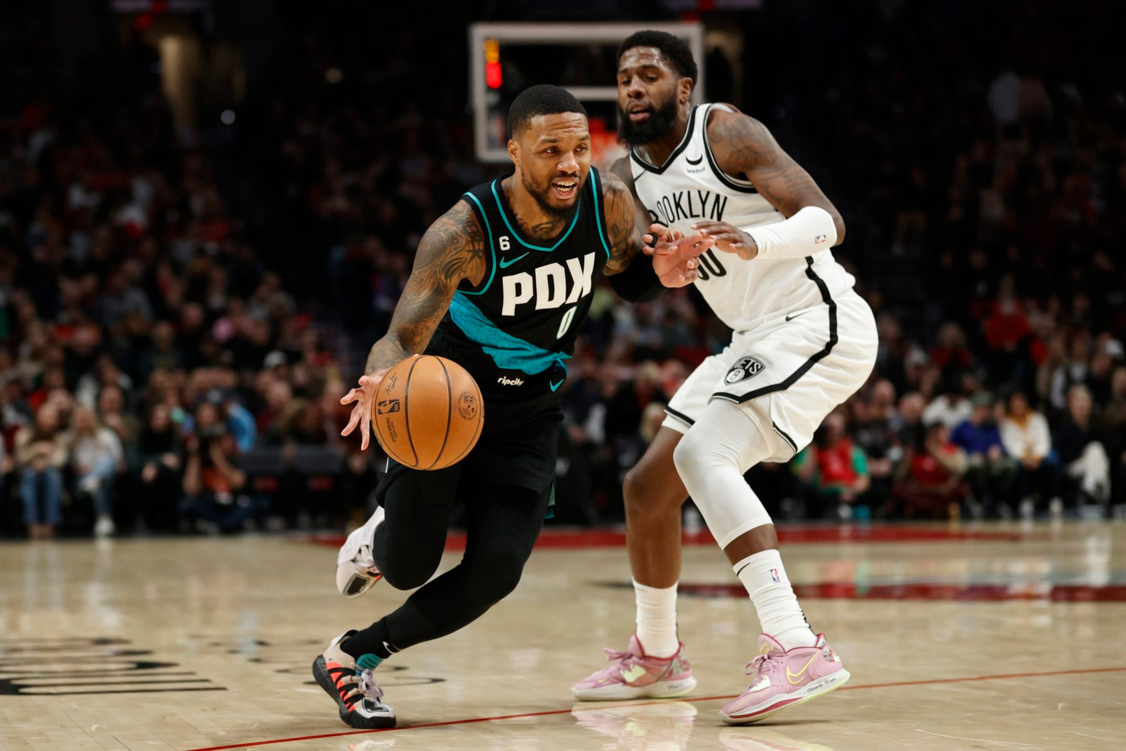 PORTLAND, OREGON - NOVEMBER 17: Damian Lillard #0 of the Portland Trail Blazers dribbles against Royce O'Neale #00 of the Brooklyn Nets during the third quarter at Moda Center on November 17, 2022 in Portland, Oregon. NOTE TO USER: User expressly acknowledges and agrees that, by downloading and or using this photograph, User is consenting to the terms and conditions of the Getty Images License Agreement. (Photo by Steph Chambers/Getty Images)
