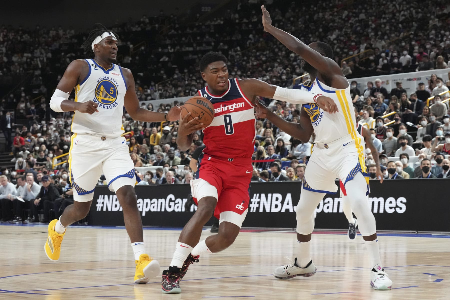 Washington Wizards' Rui Hachimura, center, drives around Golden State Warriors' Kevon Looney, left, and Draymond Green during their preseason NBA basketball game, Friday, Sept. 30, 2022, at Saitama Super Arena, in Saitama, north of Tokyo. (AP Photo/Eugene Hoshiko)