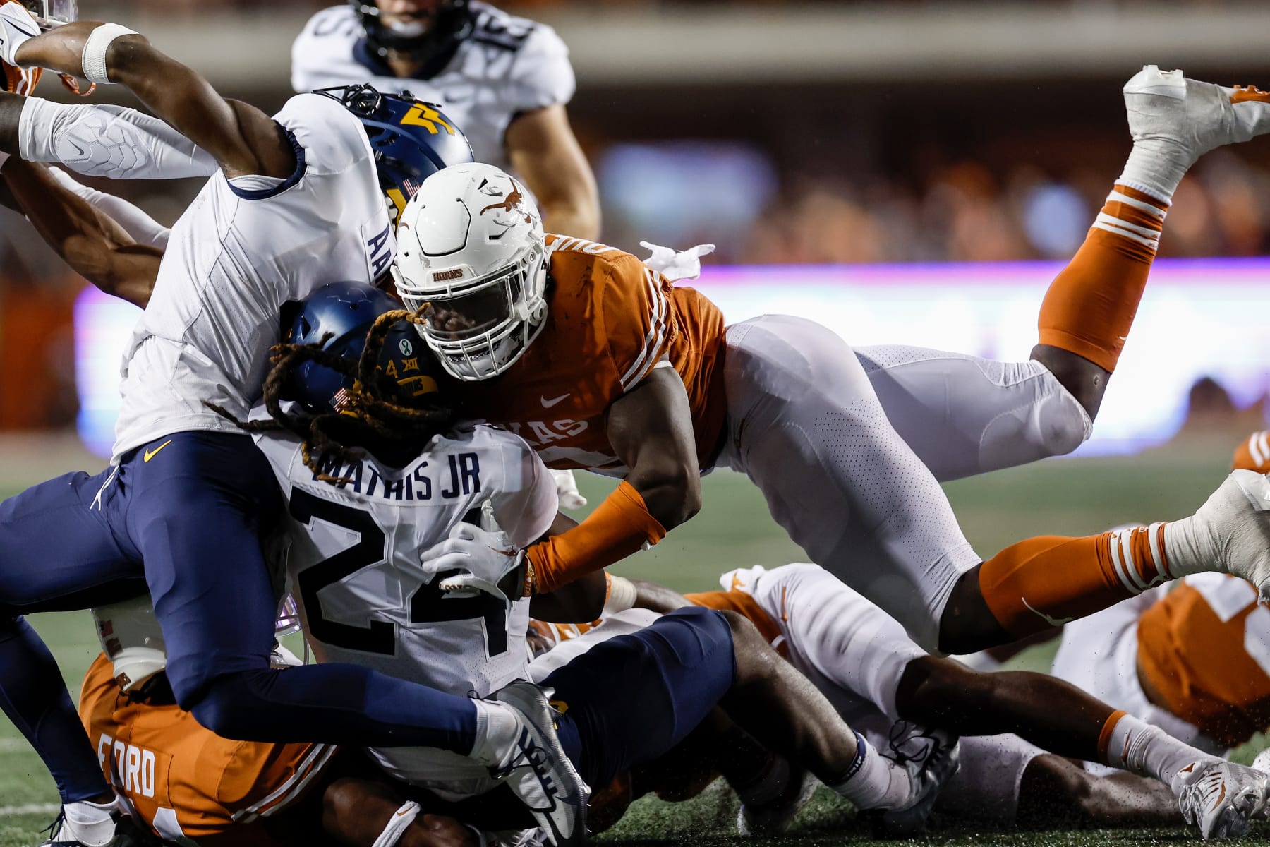 AUSTIN, TEXAS - OCTOBER 01: Tony Mathis Jr. #24 of the West Virginia Mountaineers is tackled by Jaylan Ford #41 of the Texas Longhorns and DeMarvion Overshown #0 in the second half at Darrell K Royal-Texas Memorial Stadium on October 01, 2022 in Austin, Texas. (Photo by Tim Warner/Getty Images)