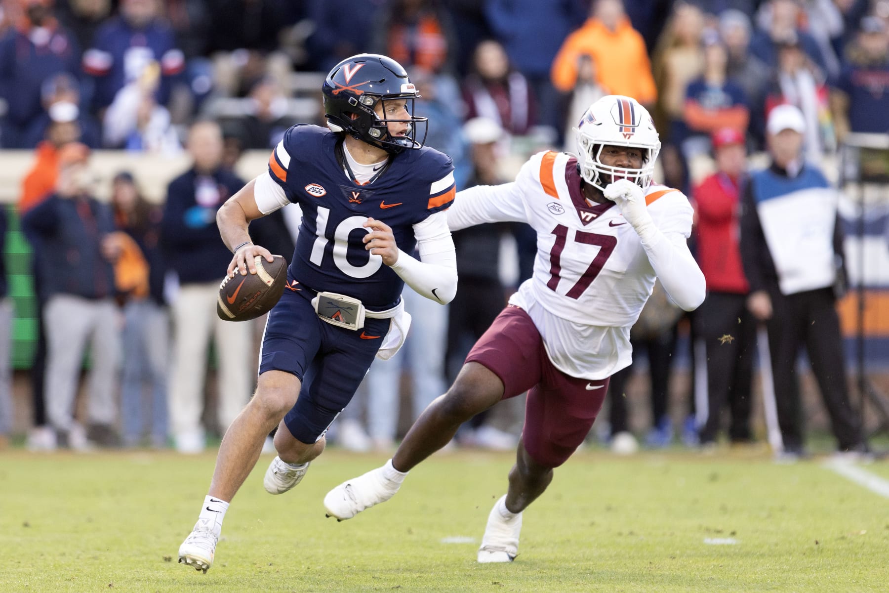 CHARLOTTESVILLE, VIRGINIA - NOVEMBER 25: Anthony Colandrea #10 of the Virginia Cavaliers scrambles under pressure from Cole Nelson #17 of the Virginia Tech Hokies in the first half during a game at Scott Stadium on November 25, 2023 in Charlottesville, Virginia. (Photo by Ryan M. Kelly/Getty Images)