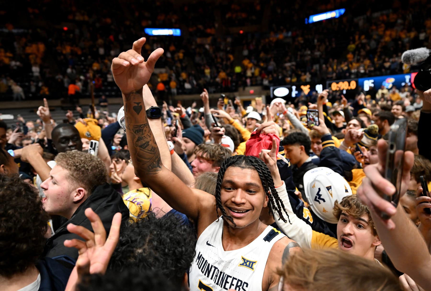 MORGANTOWN, WEST VIRGINIA - JANUARY 20: RaeQuan Battle #21 of the West Virginia Mountaineers celebrates with fans after a 91-85 victory agains the Kansas Jayhawks at WVU Coliseum on January 20, 2024 in Morgantown, West Virginia. (Photo by Greg Fiume/Getty Images)
