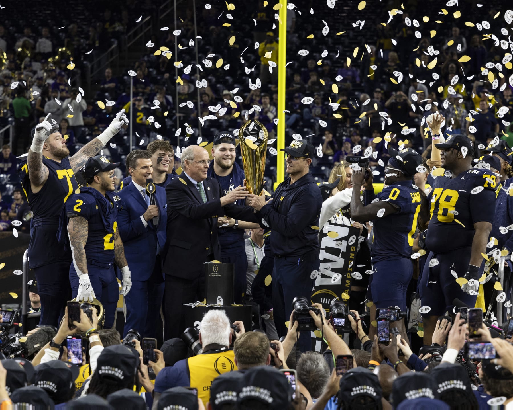 HOUSTON, TX - JANUARY 8: Head Coach Jim Harbaugh of the Michigan Wolverines is presented the trophy as National Champion after the CFP National Championship game between University of Washington and University of Michigan at NRG Stadium on January 8, 2024 in Houston, Texas. (Photo by Steve Limentani/ISI Photos/Getty Images)