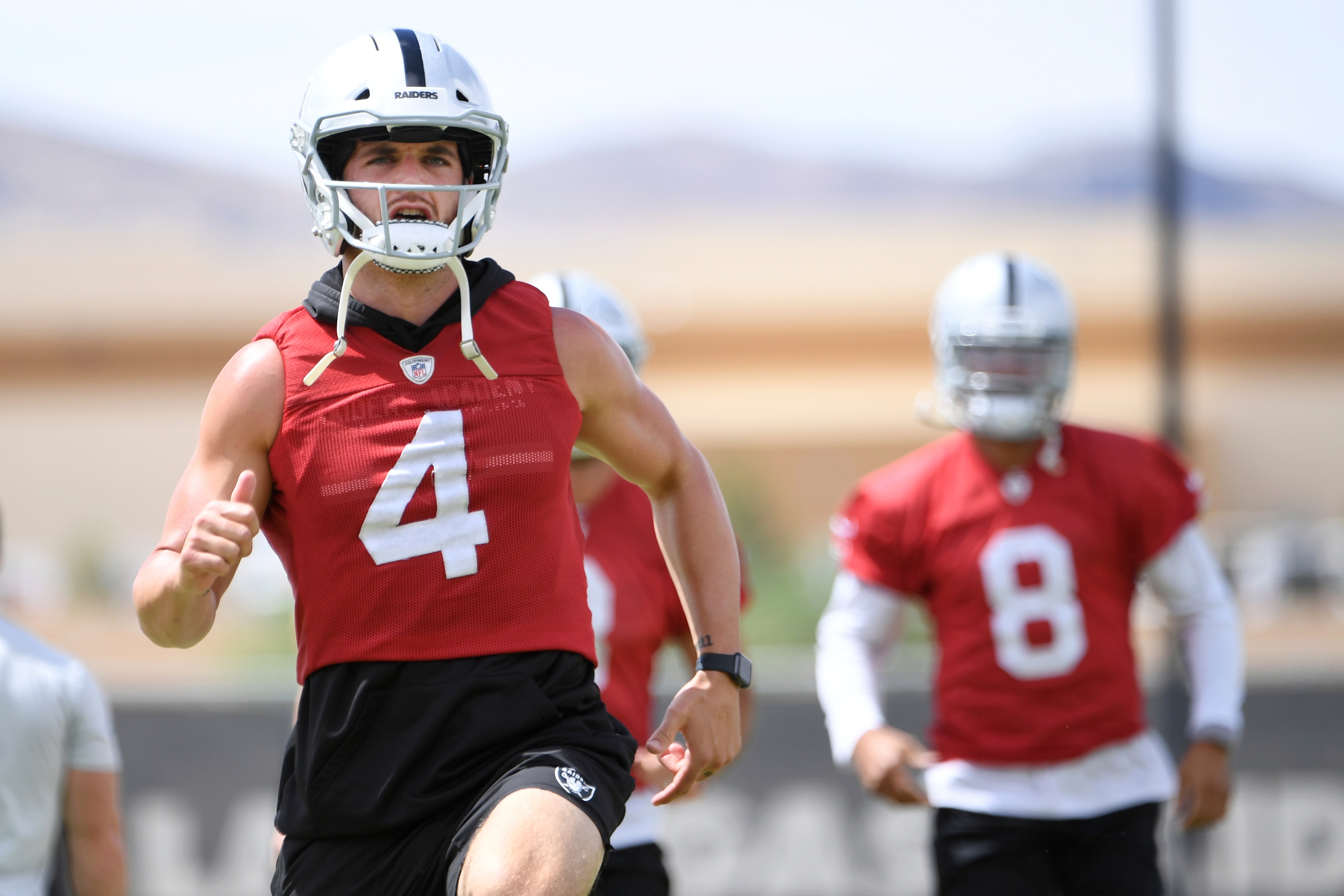 Las Vegas Raiders quarterbacks Derek Carr (4) and Marcus Mariota (8) warm up during an NFL football organized team activity at the team's training facility Wednesday, May 26, 2021, in Henderson, Nev. (AP Photo/David Becker)