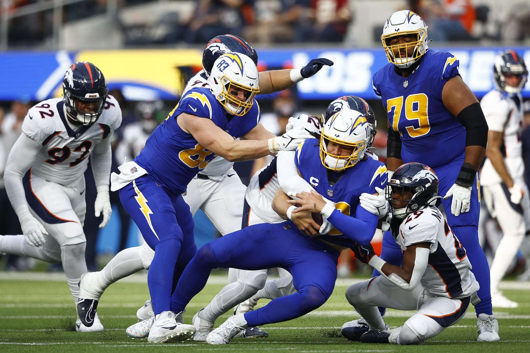 INGLEWOOD, CALIFORNIA - DECEMBER 10: Justin Herbert #10 of the Los Angeles Chargers is sacked by Ja'Quan McMillian #29 of the Denver Broncos and Delarrin Turner-Yell #32 of the Denver Broncos during the first quarter at SoFi Stadium on December 10, 2023 in Inglewood, California. (Photo by Ronald Martinez/Getty Images)
