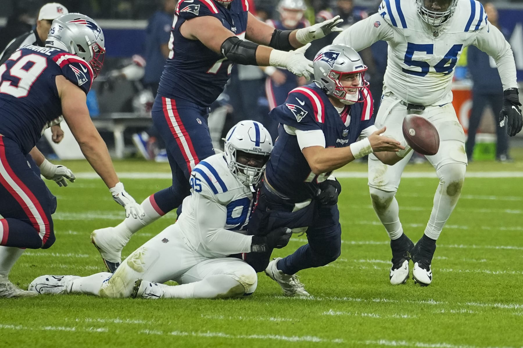 New England Patriots quarterback Mac Jones (10) pitches out as Indianapolis Colts defensive end Adetomiwa Adebawore (95) tries to tackle in the second half of an NFL football game in Frankfurt, Germany Sunday, Nov. 12, 2023. (AP Photo/Martin Meissner)