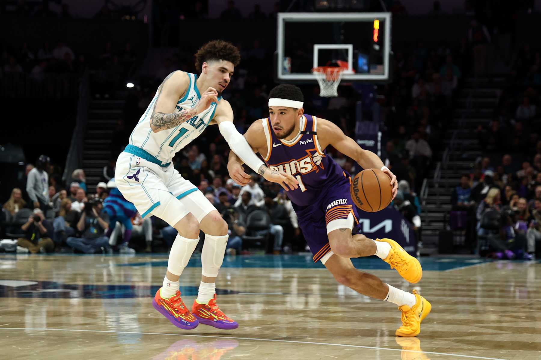 CHARLOTTE, NORTH CAROLINA - JANUARY 07: Devin Booker #1 of the Phoenix Suns drives to the basket against LaMelo Ball #1 of the Charlotte Hornets during the first half of game at Spectrum Center on January 07, 2025 in Charlotte, North Carolina. NOTE TO USER: User expressly acknowledges and agrees that, by downloading and or using this photograph, User is consenting to the terms and conditions of the Getty Images License Agreement. (Photo by Jared C. Tilton/Getty Images)