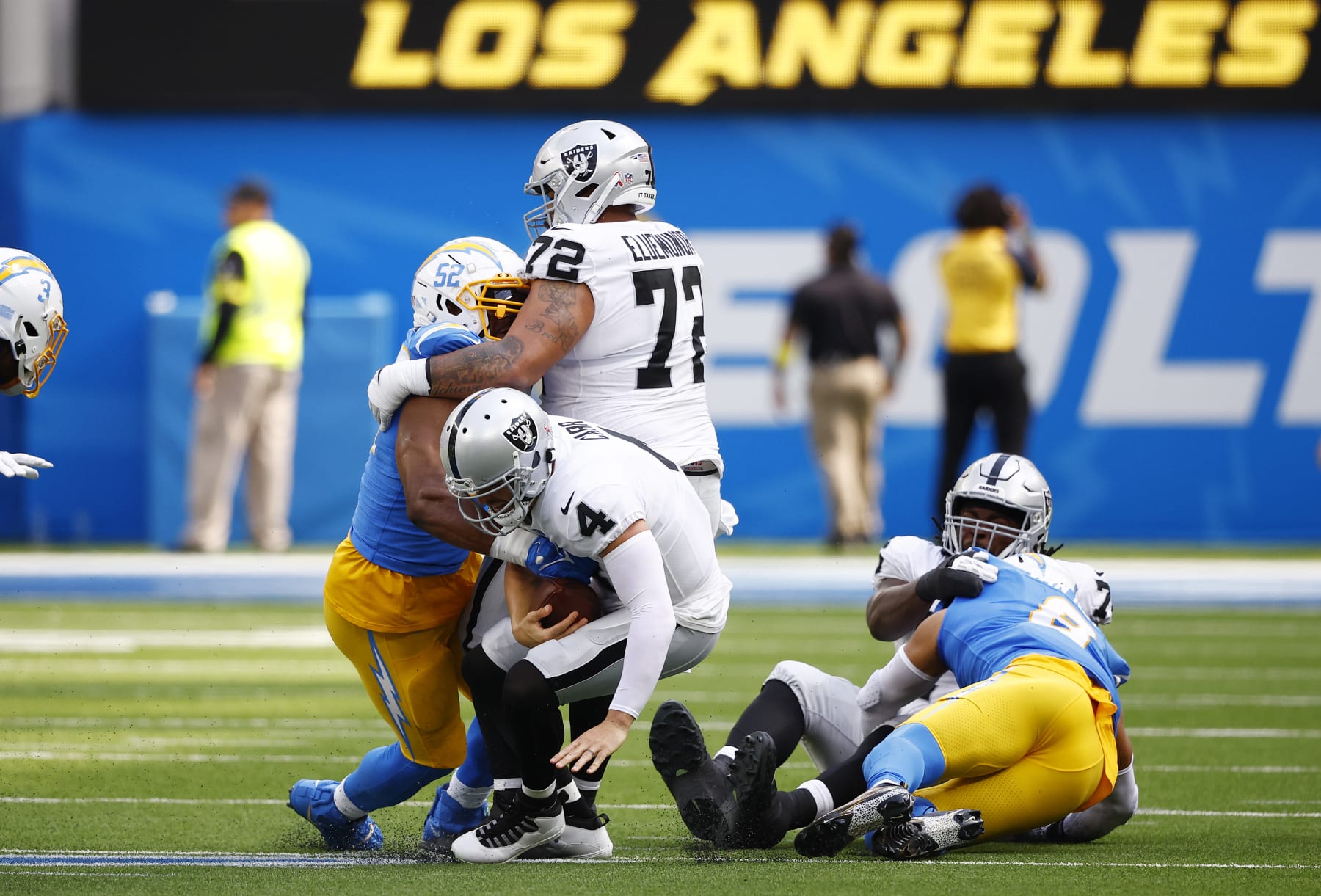 INGLEWOOD, CALIFORNIA - SEPTEMBER 11: Linebacker Khalil Mack #52 of the Los Angeles Chargers and guard Jermaine Eluemunor #72 of the Las Vegas Raiders fall on top of quarterback Derek Carr #4 of the Las Vegas Raiders during the first half at SoFi Stadium on September 11, 2022 in Inglewood, California. (Photo by Ronald Martinez/Getty Images)