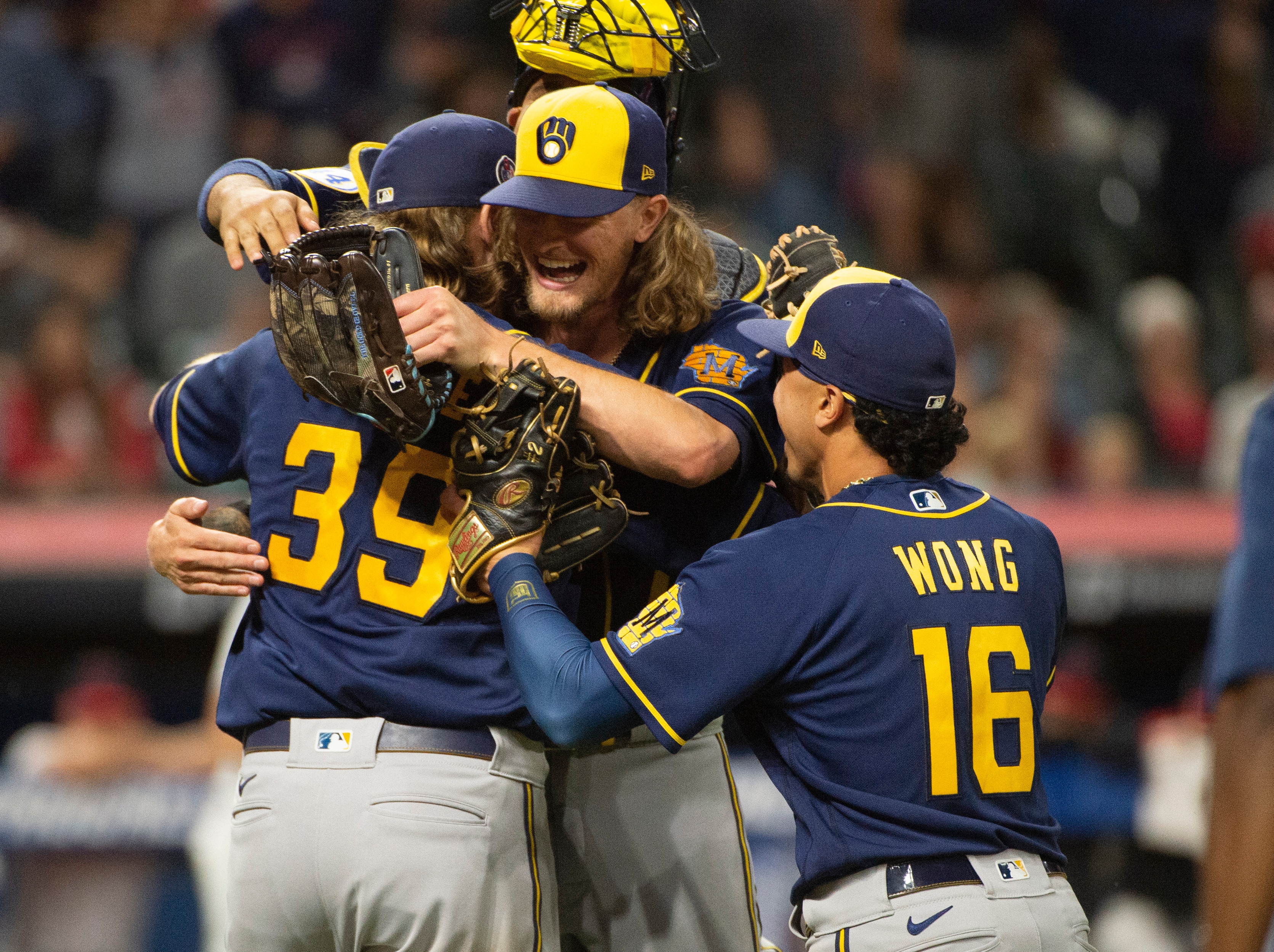 Milwaukee Brewers starter Corbin Burnes (39) hugs reliever Josh Hader as they celebrate after pitching a combined no-hitter against the Cleveland Indians in a baseball game in Cleveland, Saturday, Sept. 11, 2021. Brewers' Kolten Wong (16) also joins the celebration. (AP Photo/Phil Long)