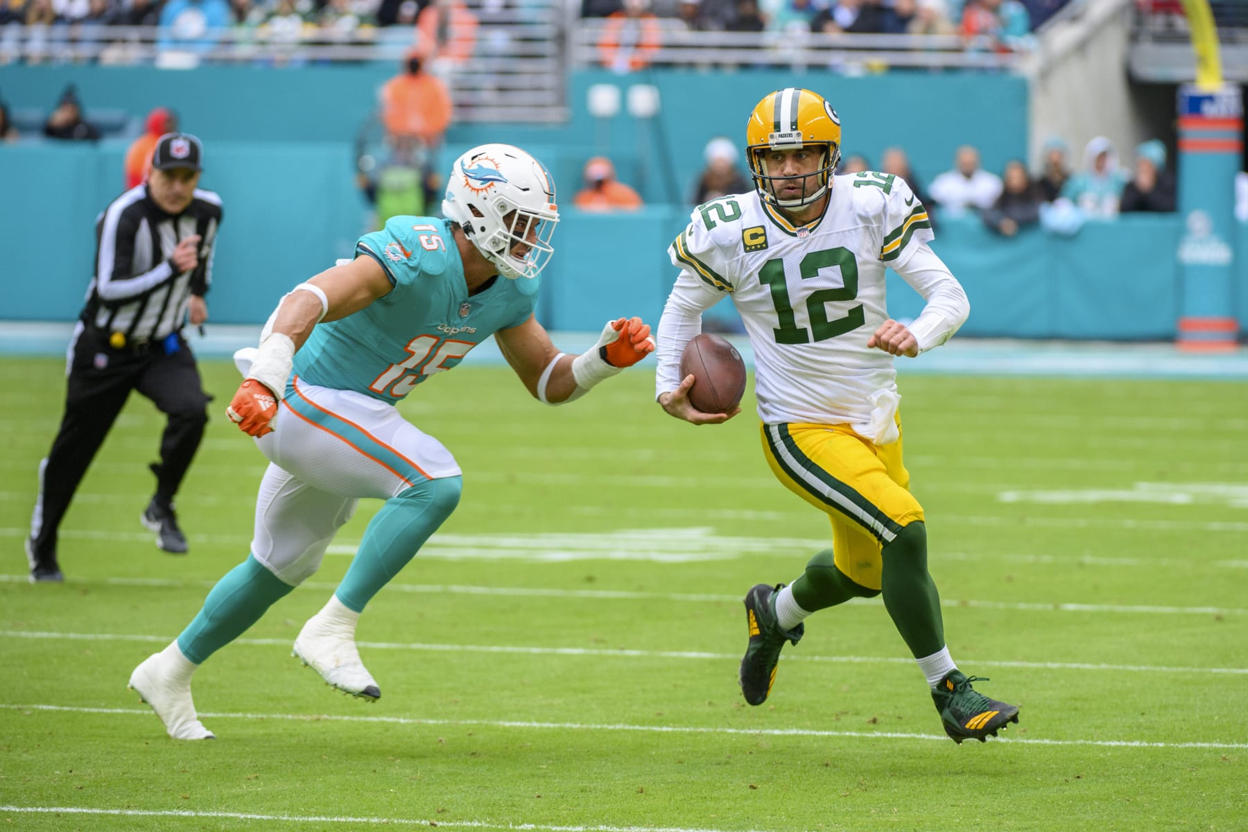 Green Bay Packers quarterback Aaron Rodgers (12) runs with the ball and is tackled by Miami Dolphins linebacker Jaelan Phillips (15) during an NFL football game, Sunday, Dec. 25, 2022, in Miami Gardens, Fla. (AP Photo/Doug Murray)