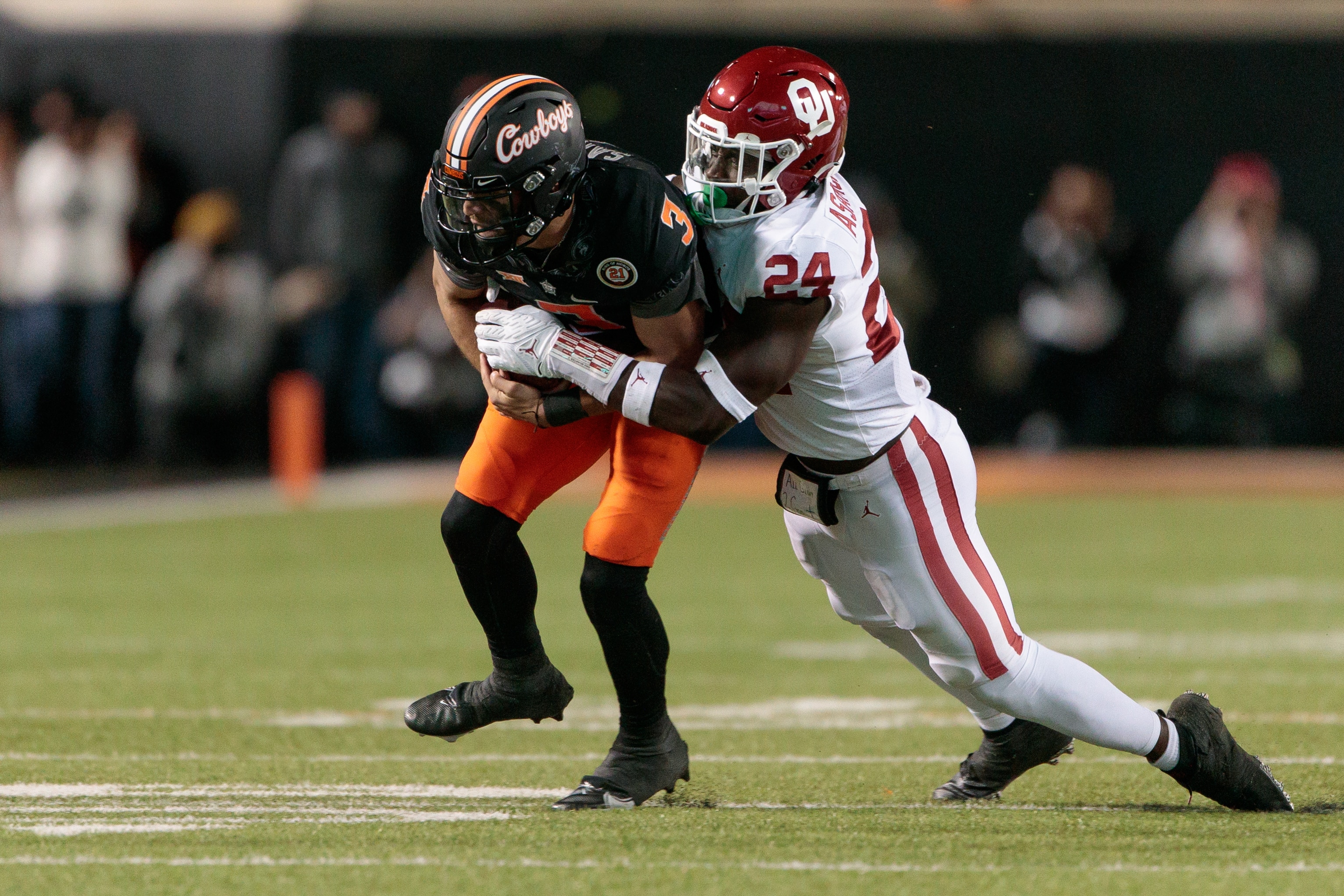 STILLWATER, OK - NOVEMBER 27: Oklahoma Sooners linebacker Brian Asamoah (24) tackles Oklahoma State Cowboys quarterback Spencer Sanders (3) on November 27th, 2021 at Boone Pickens Stadium in Stillwater, Oklahoma. (Photo by William Purnell/Icon Sportswire via Getty Images)