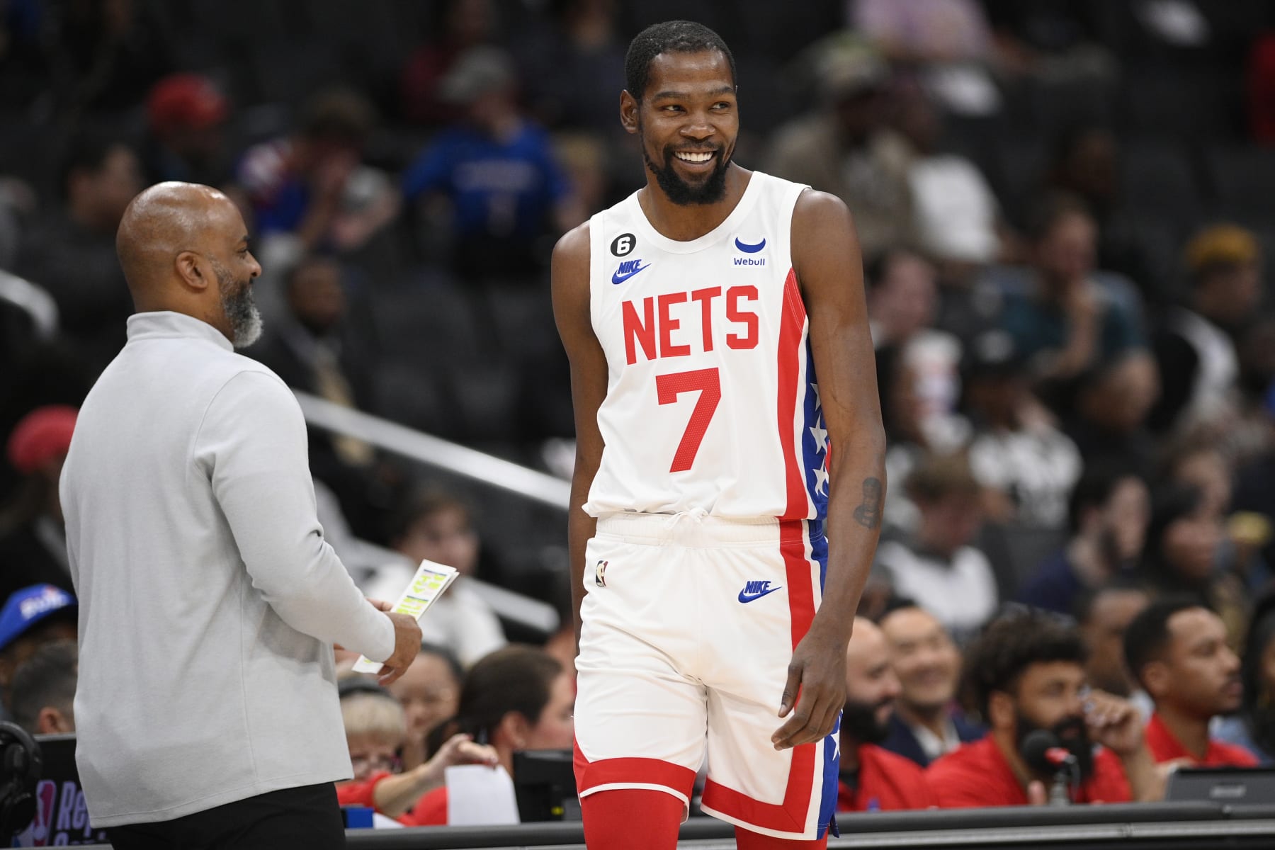 Brooklyn Nets forward Kevin Durant (7) smiles at Washington Wizards head coach Wes Unseld Jr., left, during the first half of an NBA basketball game, Friday, Nov. 4, 2022, in Washington. (AP Photo/Nick Wass)