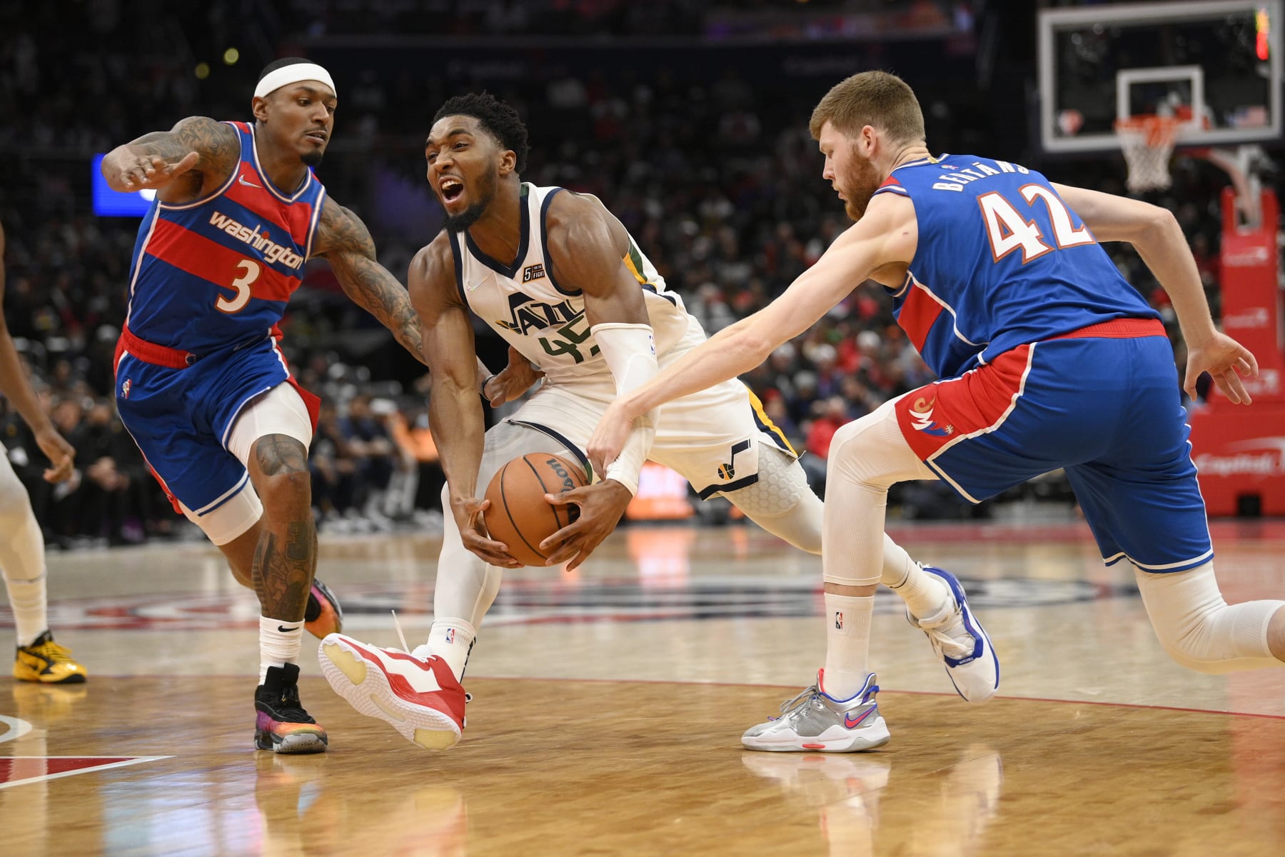 Utah Jazz guard Donovan Mitchell (45) drives to the basket against Washington Wizards guard Bradley Beal (3) and forward Davis Bertans (42) during the first half of an NBA basketball game Saturday, Dec. 11, 2021, in Washington. (AP Photo/Nick Wass)