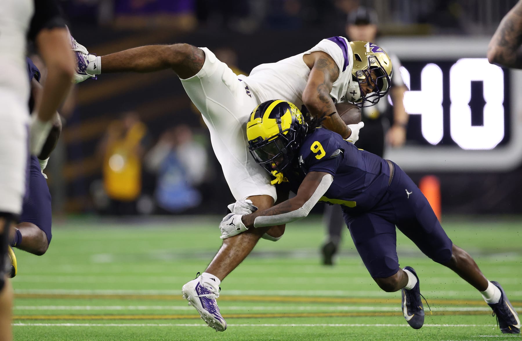 HOUSTON, TEXAS - JANUARY 08: Ja'Lynn Polk #2 of the Washington Huskies is tackled by Rod Moore #9 of the Michigan Wolverines in the third quarter during the 2024 CFP National Championship game at NRG Stadium on January 08, 2024 in Houston, Texas. (Photo by Gregory Shamus/Getty Images)