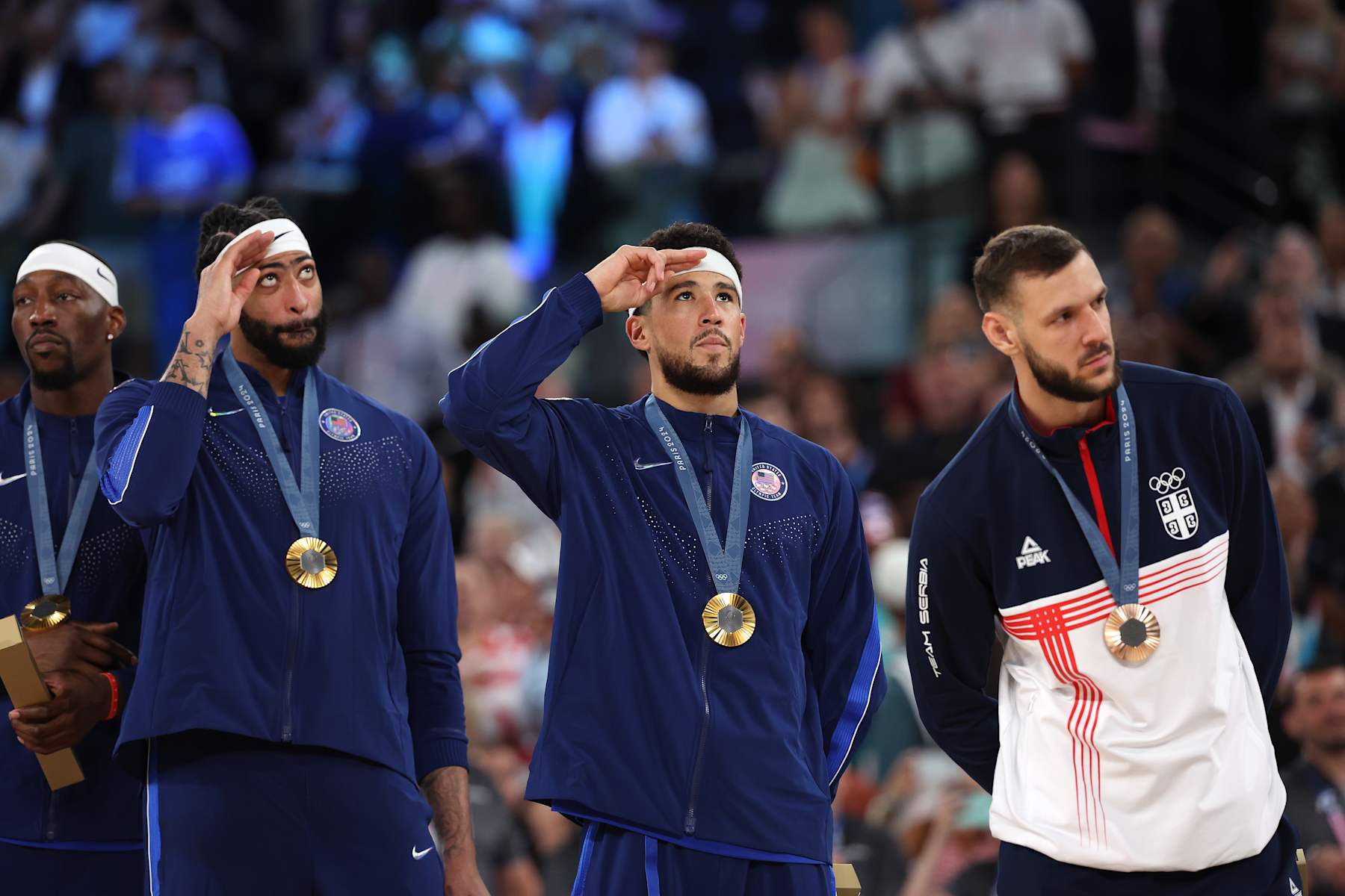 PARIS, FRANCE - AUGUST 10: Gold medalists Anthony Davis and Devin Booker of Team United States stand for their nation's national anthem on the podium during the Men's basketball medal ceremony on day fifteen of the Olympic Games Paris 2024 at Bercy Arena on August 10, 2024 in Paris, France. (Photo by Ezra Shaw/Getty Images)
