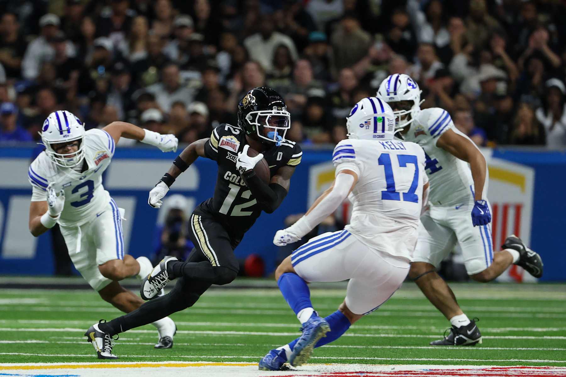 SAN ANTONIO, TX - DECEMBER 28: Colorado Buffaloes wide receiver Travis Hunter (12) runs with the ball after a reception and tries to avoid Brigham Young Cougars linebacker Jack Kelly (17) during the football game between BYU Cougars and Colorado Buffalos on December 28, 2024, at the Alamodome in San Antonio, Texas. (Photo by David Buono/Icon Sportswire via Getty Images)