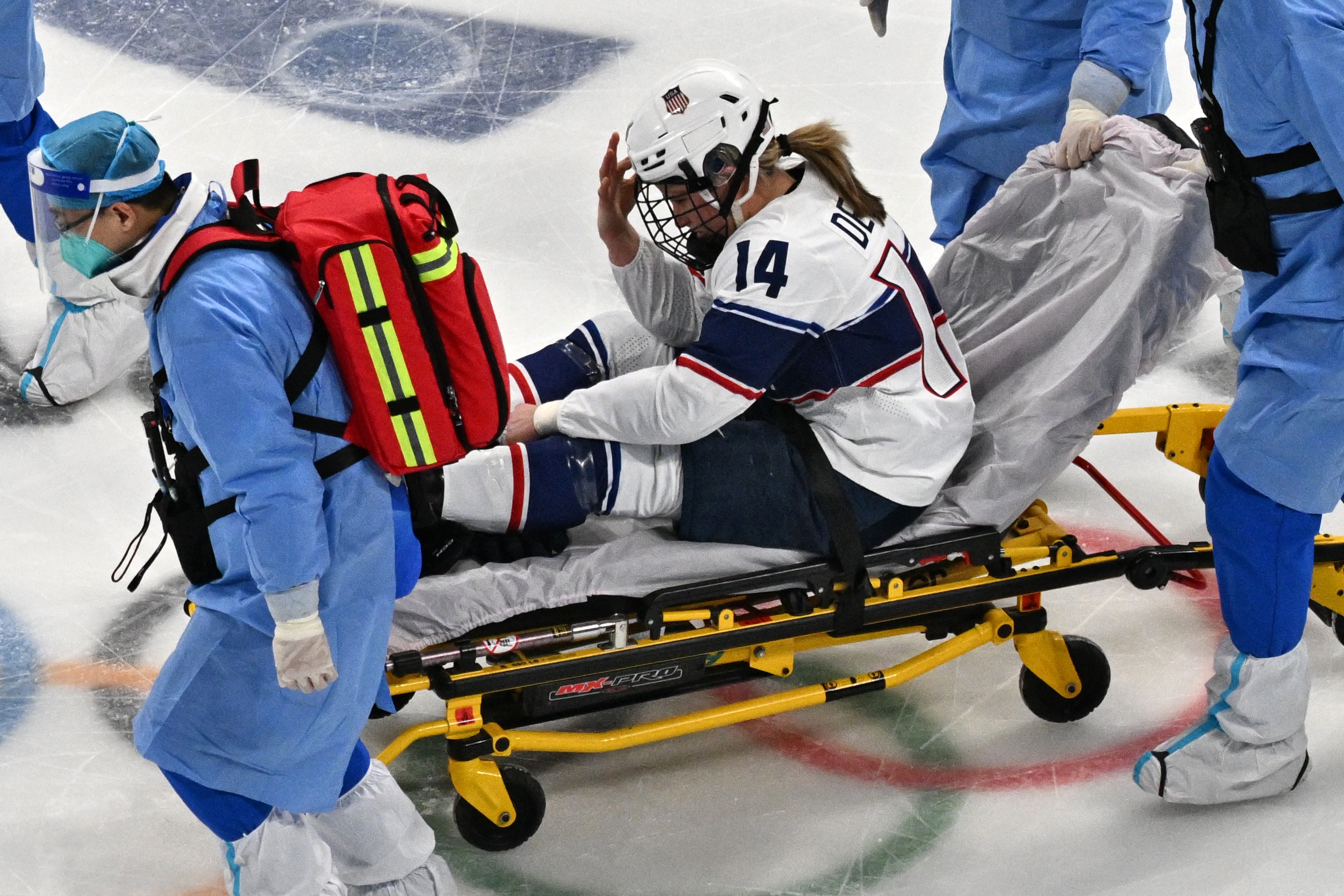 USA's Brianna Decker is taken out of the rink on a trolley after colliding with Finland's Ronja Savolainen (out of frame) during their women's preliminary round group A match of the Beijing 2022 Winter Olympic Games ice hockey competition, at the Wukesong Sports Centre in Beijing on February 3, 2022. (Photo by ANTHONY WALLACE / AFP) (Photo by ANTHONY WALLACE/AFP via Getty Images)