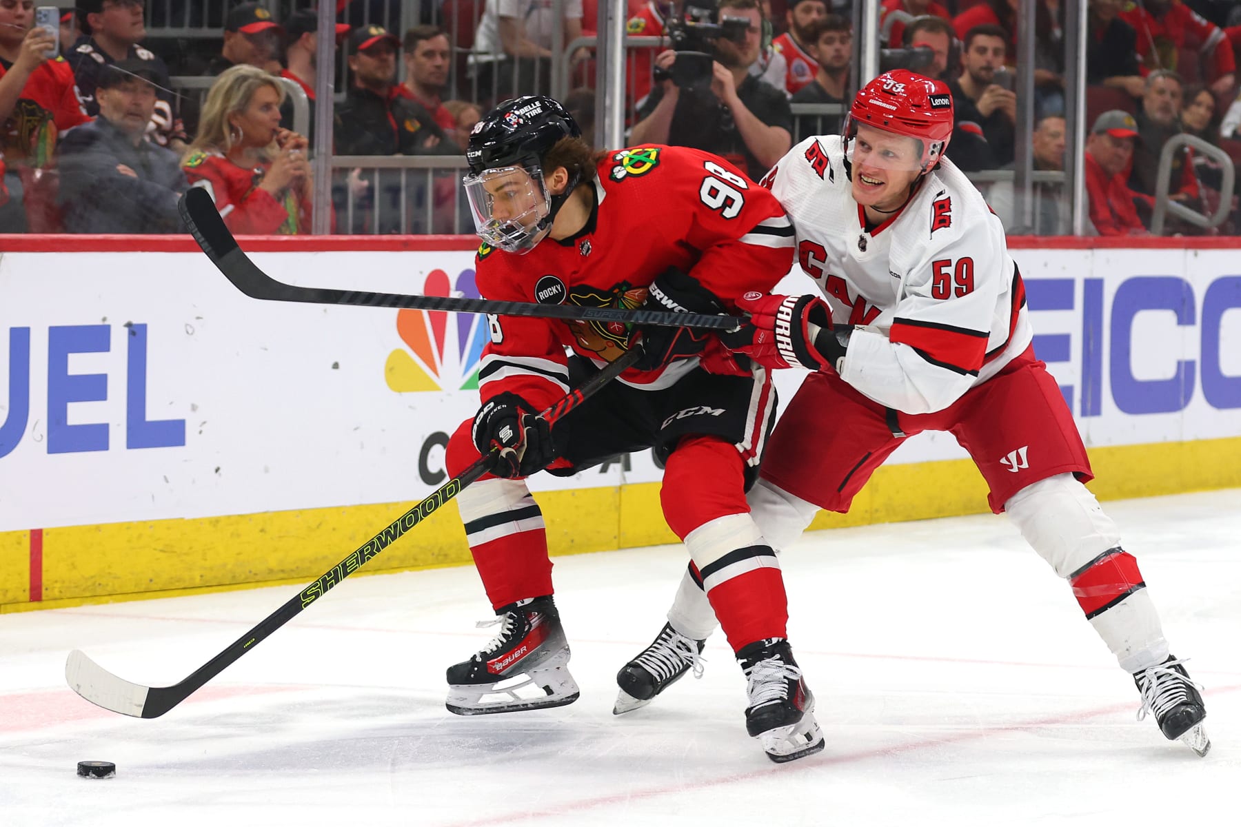 CHICAGO, ILLINOIS - APRIL 14: Connor Bedard #98 of the Chicago Blackhawks and Jake Guentzel #59 of the Carolina Hurricanes battle for control of the puck during the first period at the United Center on April 14, 2024 in Chicago, Illinois. (Photo by Michael Reaves/Getty Images)