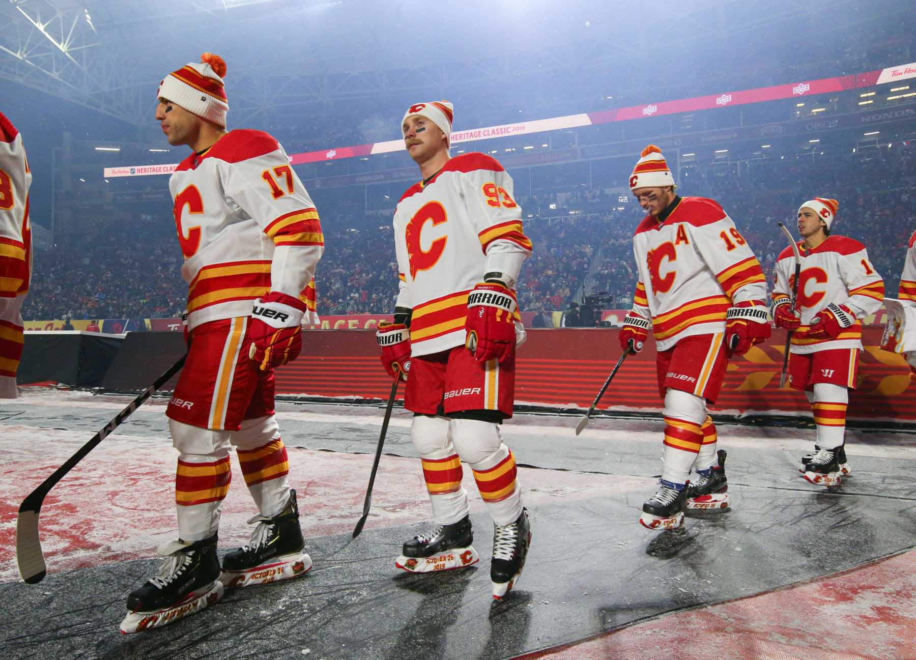 REGINA, SK - OCTOBER 26: Milan Lucic #17, Sam Bennett #93 and Matthew Tkachuk #19 of the Calgary Flames walk to the ice before taking on the Winnipeg Jets during the 2019 Tim Hortons NHL Heritage Classic at Mosaic Stadium on October 26, 2019 in Regina, Saskatchewan, Canada.  (Photo by Andre Ringuette/NHLI via Getty Images)
