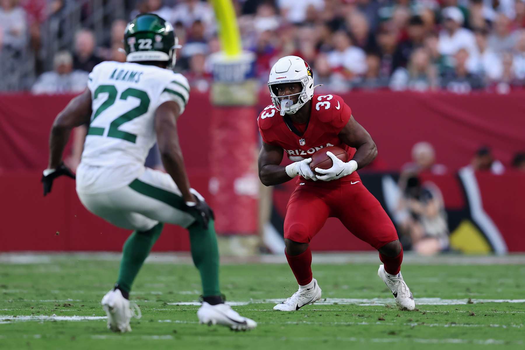 GLENDALE, ARIZONA - NOVEMBER 10: Trey Benson #33 of the Arizona Cardinals runs with the ball while being chased by Tony Adams #22 of the New York Jets in the third quarter at State Farm Stadium on November 10, 2024 in Glendale, Arizona. (Photo by Chris Coduto/Getty Images)