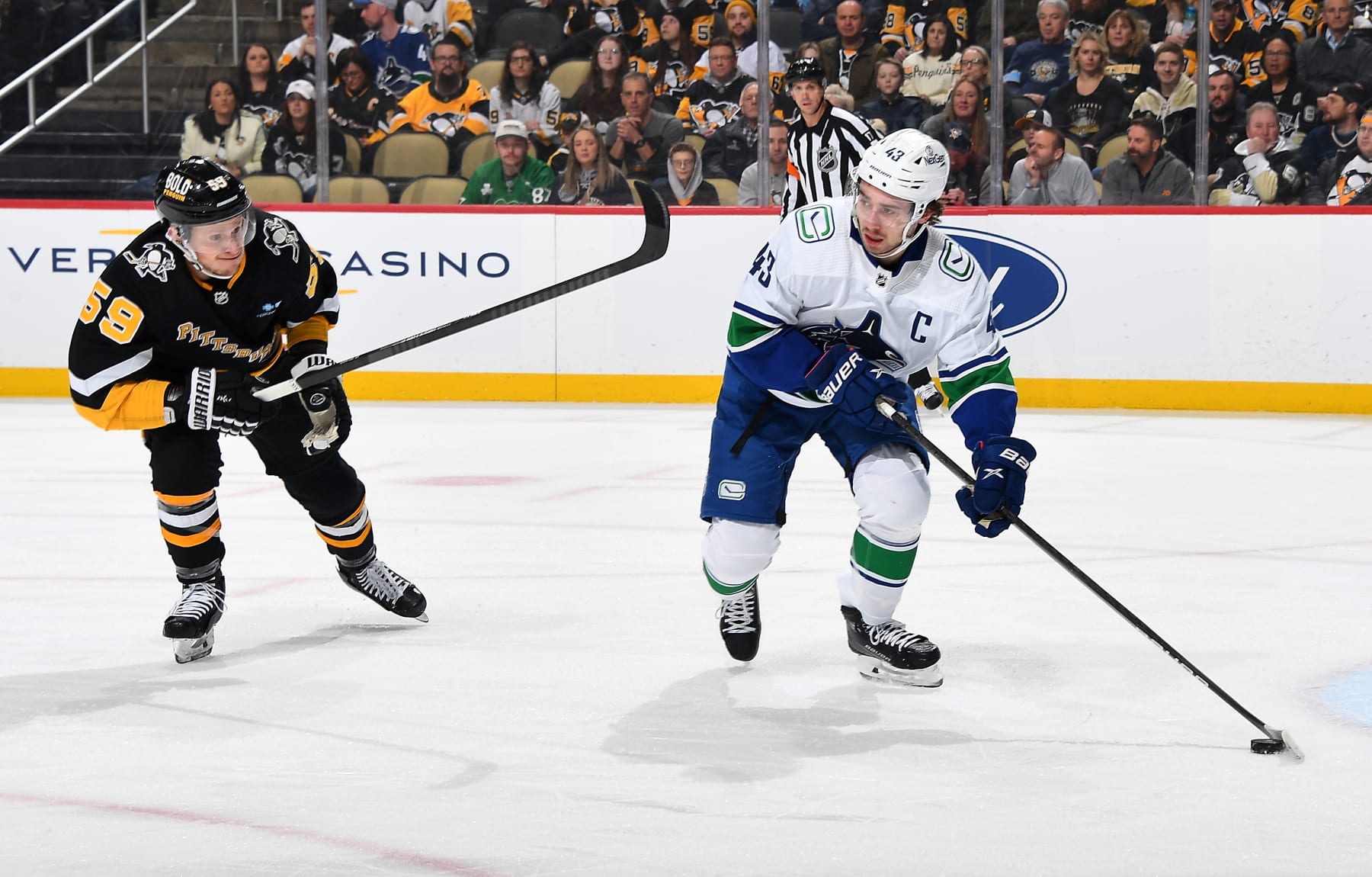 PITTSBURGH, PENNSYLVANIA - JANUARY 11:  Quinn Hughes #43 of the Vancouver Canucks moves the puck in front of Jake Guentzel #59 of the Pittsburgh Penguins at PPG PAINTS Arena on January 11, 2024 in Pittsburgh, Pennsylvania. (Photo by Joe Sargent/NHLI via Getty Images)