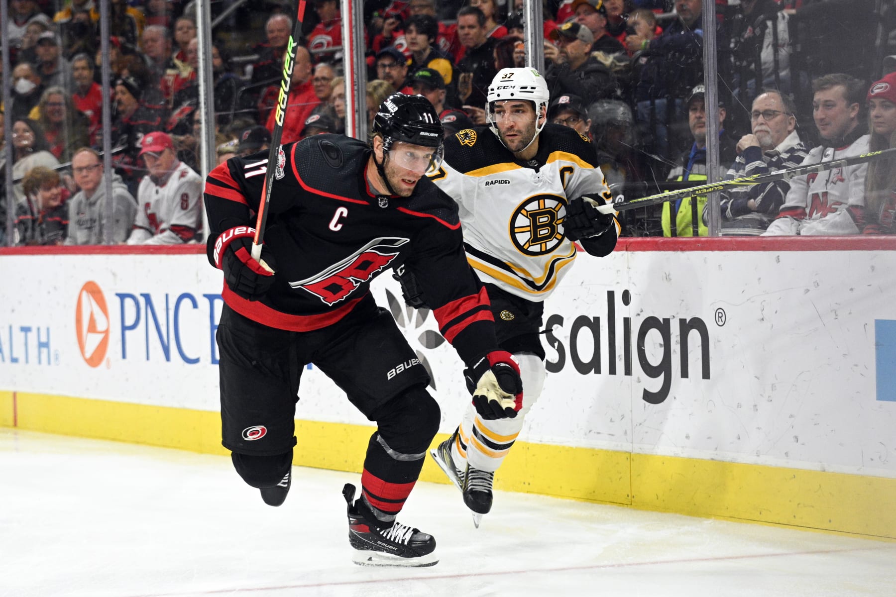 RALEIGH, NC - JANUARY 29: Carolina Hurricanes Center Jordan Staal (11) and Boston Bruins Center Patrice Bergeron (37) race to the puck during the game between the Boston Bruins and the Carolina Hurricanes on January 29, 2023 at PNC Arena in Raleigh, North Carolina. (Photo by Katherine Gawlik/Icon Sportswire via Getty Images)