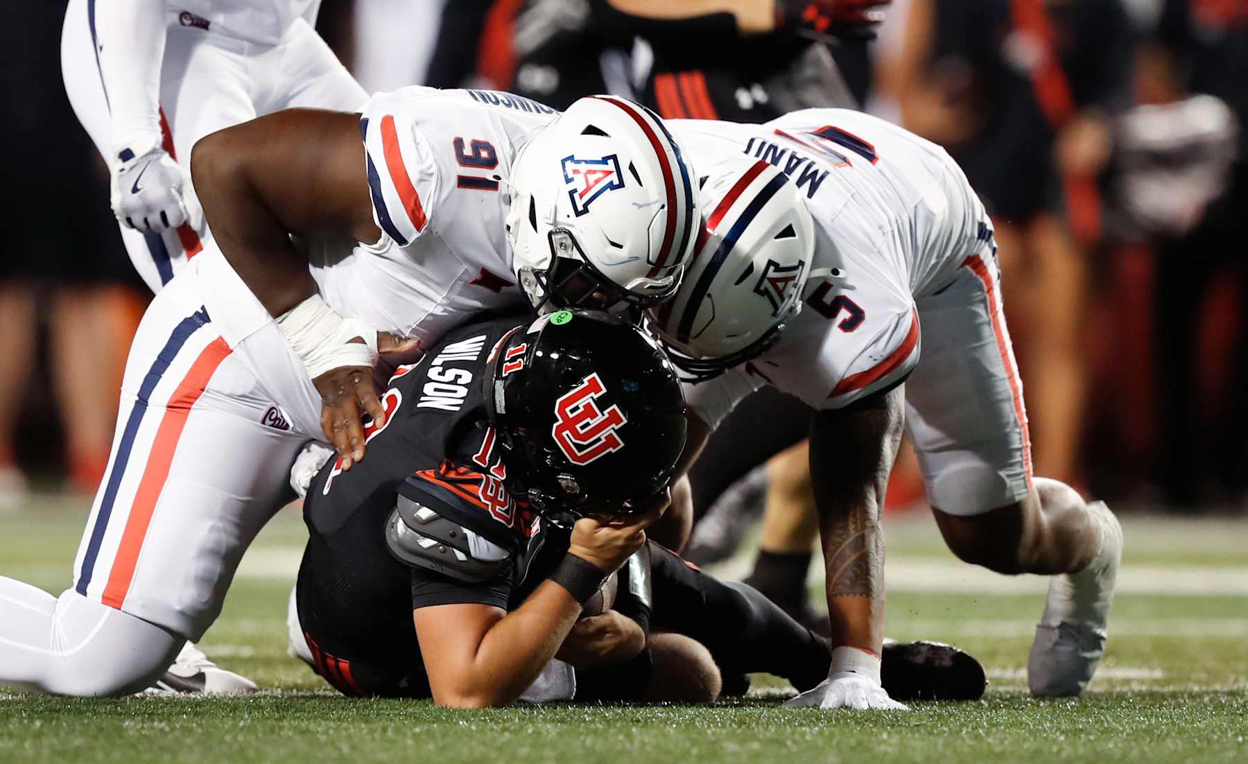 SALT LAKE CITY, UT - SEPTEMBER 28: Isaac Wilson #11 of the Utah Utes is sacked by Isaiah Johnson #91 and Jacob Manu #5 of the Arizona Wildcats during the first half of their game at Rice Eccles Stadium on September 28, 2024 in Salt Lake City, Utah. (Photo by Chris Gardner/Getty Images)