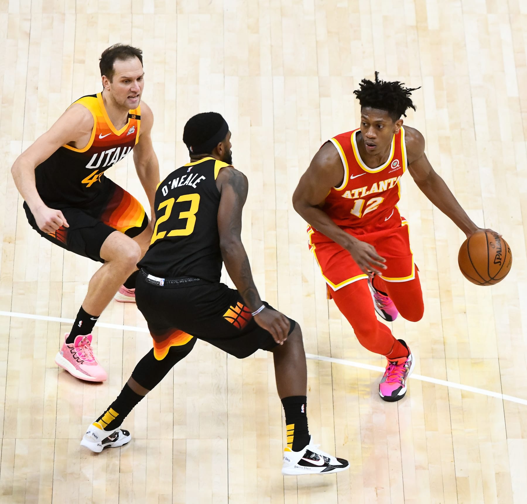 SALT LAKE CITY, UT - JANUARY 15: De'Andre Hunter #12 of the Atlanta Hawks drives around Bojan Bogdanovic #44 and Royce O'Neale #23 of the Utah Jazz during a game at Vivint Smart Home Arena on January 15, 2021 in Salt Lake City, Utah. NOTE TO USER: User expressly acknowledges and agrees that, by downloading and/or using this photograph, user is consenting to the terms and conditions of the Getty Images License Agreement.  (Photo by Alex Goodlett/Getty Images)