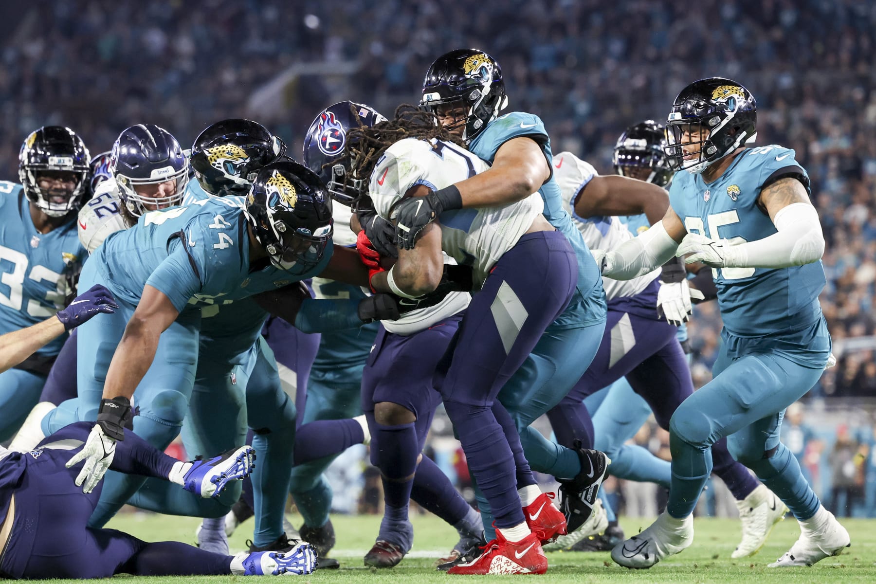 JACKSONVILLE, FLORIDA - JANUARY 07: Corey Peters #98 of the Jacksonville Jaguars and Travon Walker #44 of the Jacksonville Jaguars tackle Derrick Henry #22 of the Tennessee Titans during the fourth quarter at TIAA Bank Field on January 07, 2023 in Jacksonville, Florida. (Photo by Mike Carlson/Getty Images)