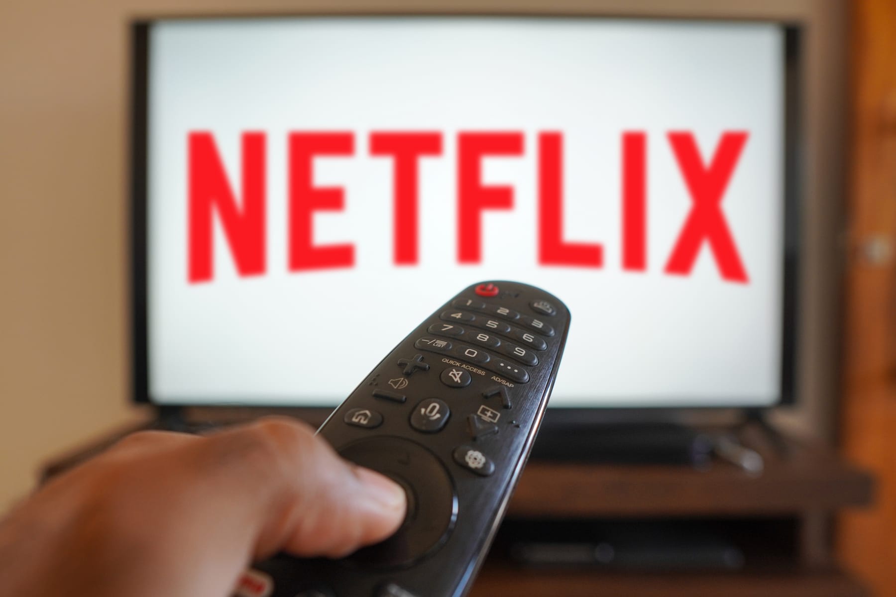 BRAZIL - 2024/05/02: In this photo illustration, a hand holding a TV remote control in front of the Netflix logo on a TV screen. (Photo Illustration by Rafael Henrique/SOPA Images/LightRocket via Getty Images)