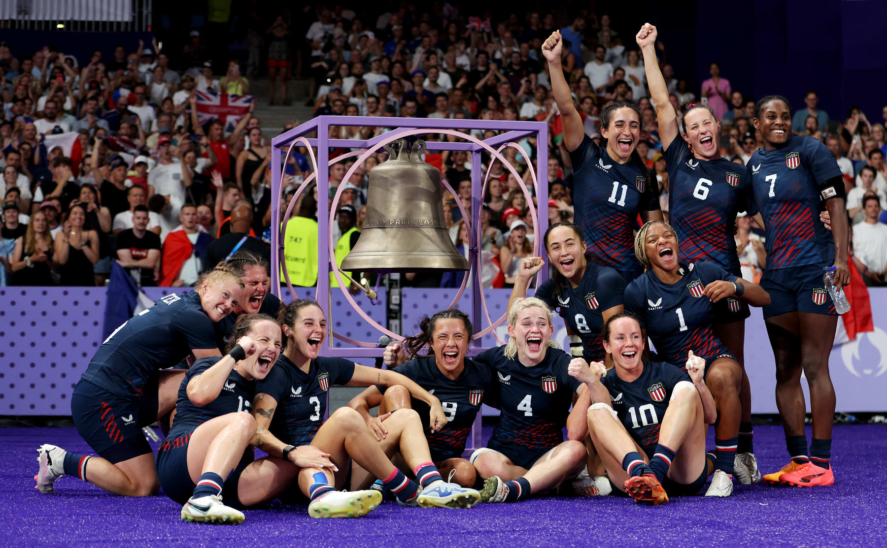 PARIS, FRANCE - JULY 29: Team United States celebrate victory as they pose for a photo with the Bell after the Women's Rugby Sevens Quarter Final match between Team Great Britain and Team United States on day three of the Olympic Games Paris 2024 at Stade de France on July 29, 2024 in Paris, France. (Photo by Michael Steele/Getty Images)